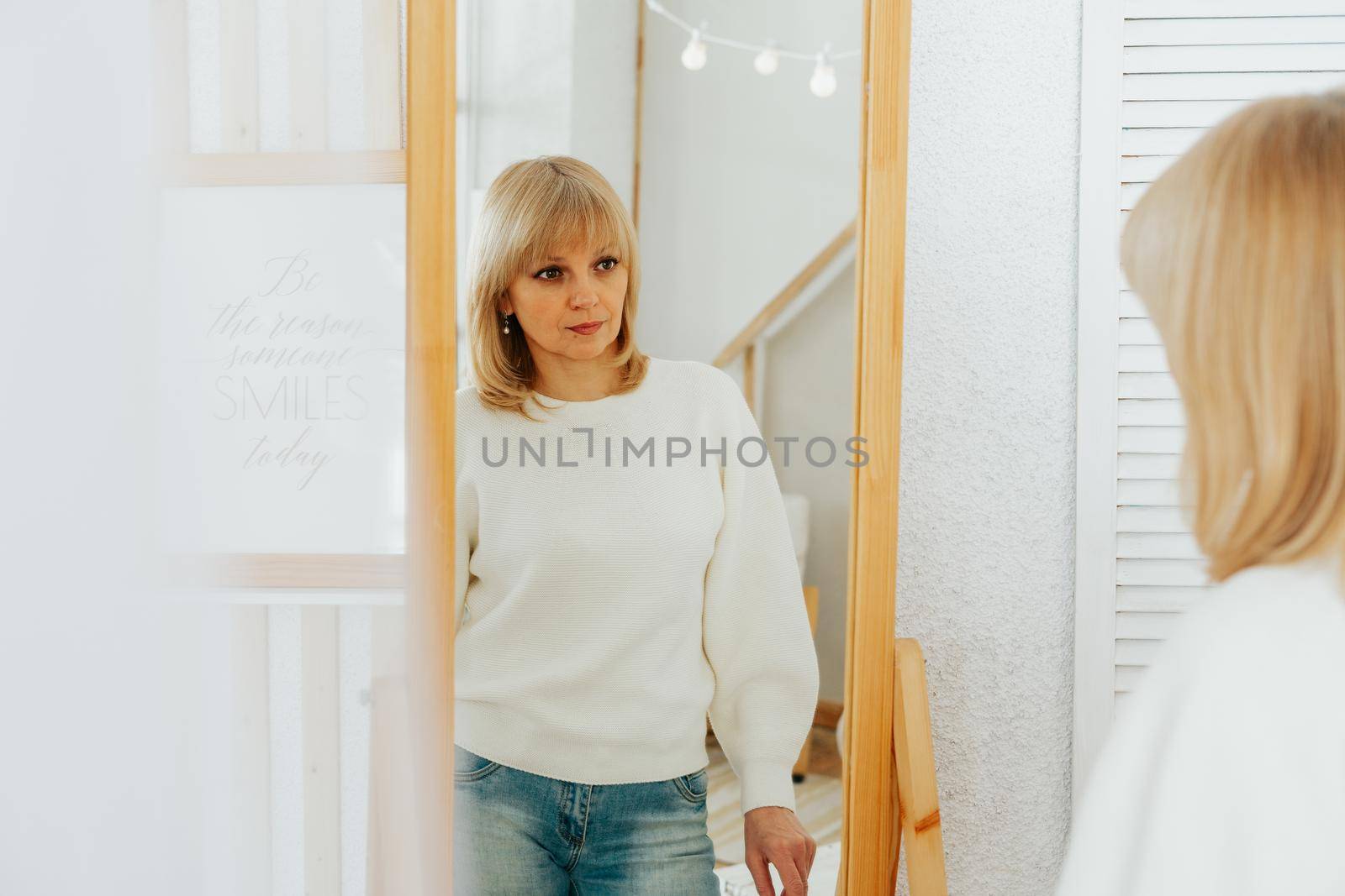 woman standing near mirror and looking at reflection by Ostanina