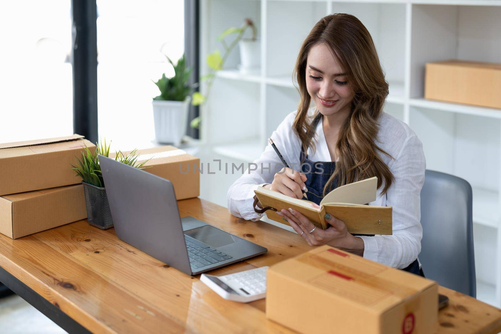 Asian woman owned business SME entrepreneur of Young Asian women working with Boxs laptop and phone for Online seller shopping at home, online marketing packaging delivery SME e-commerce concept. by nateemee
