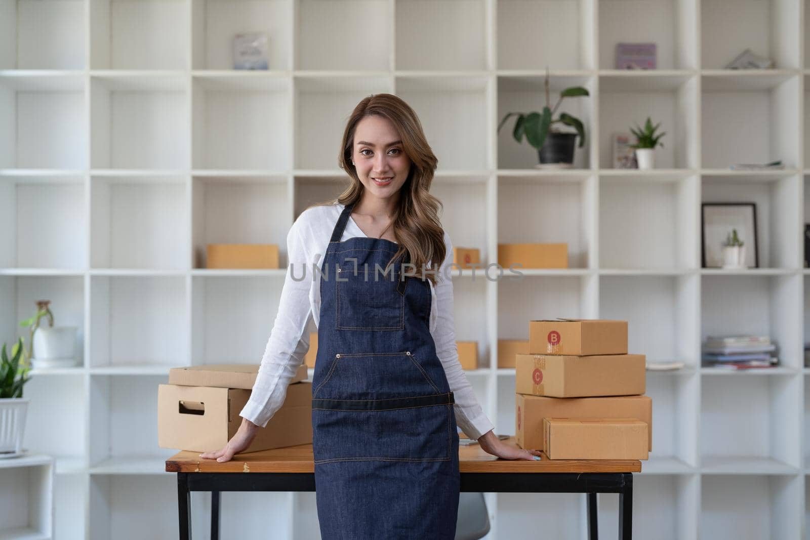 Portrait young attractive asia female owner startup business look at camera work happy with box at home prepare parcel delivery in sme supply chain, procurement, omnichannel commerce online concept. by nateemee