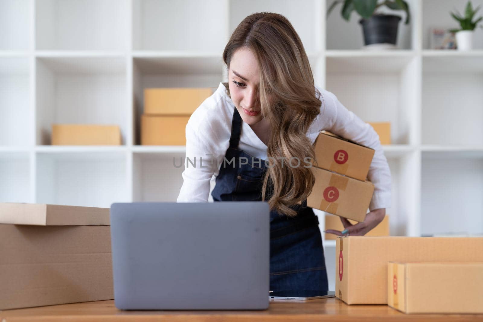 Portrait young attractive asia female owner startup business look at camera work happy with box at home prepare parcel delivery in sme supply chain, procurement, omnichannel commerce online concept. by nateemee