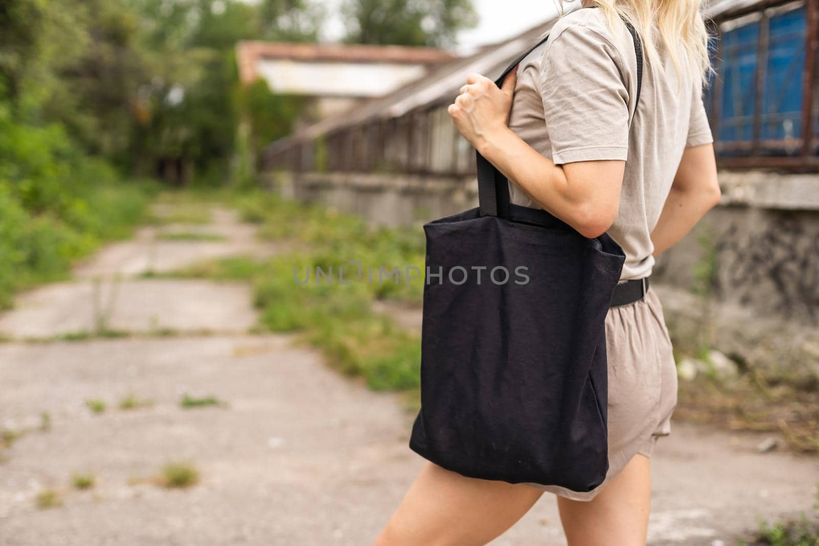 consumerism, eating and eco friendly concept - woman with reusable canvas bag for food shopping over green natural background.