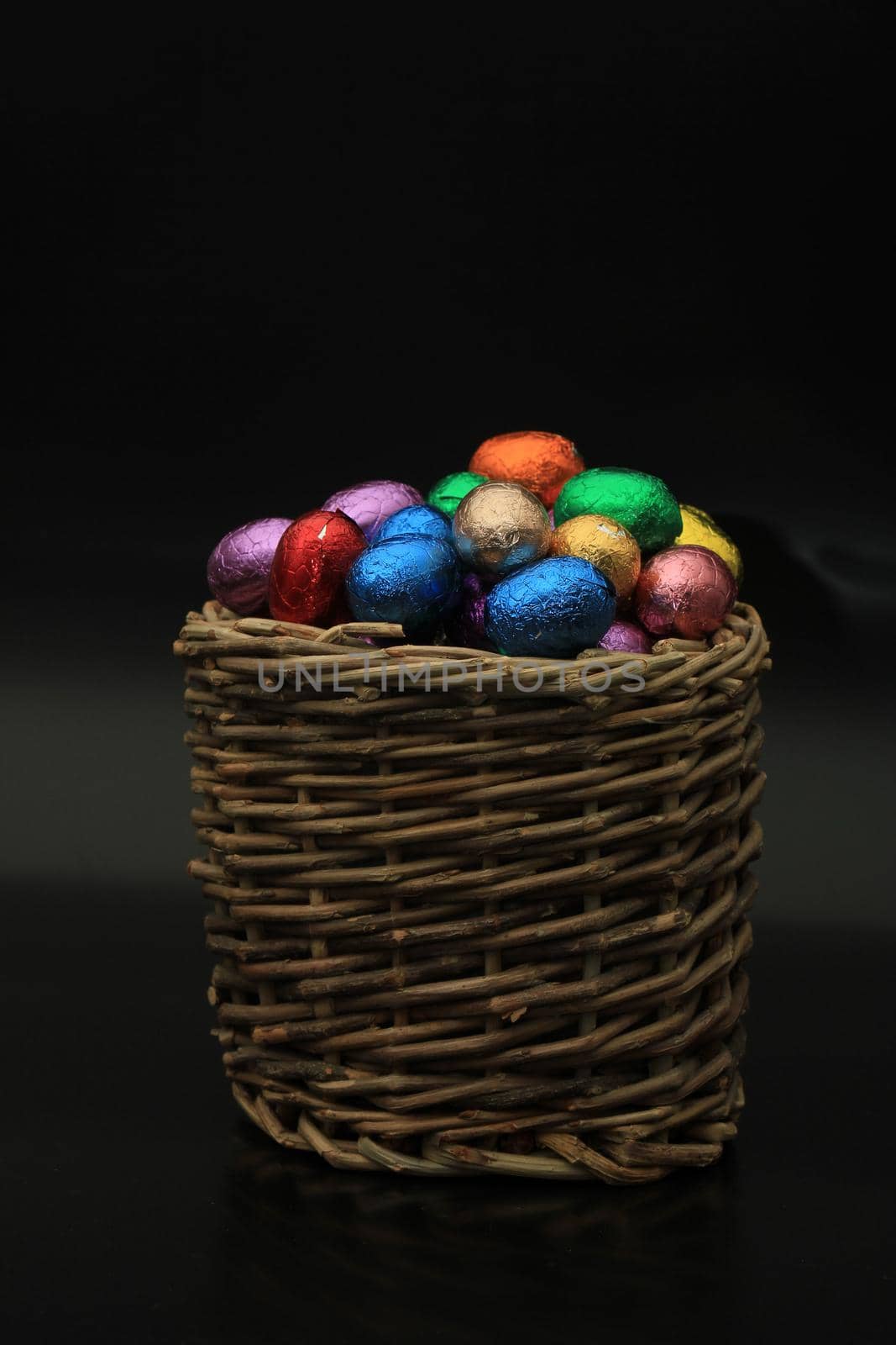 Foil wrapped chocolate easter eggs in a wicker basket