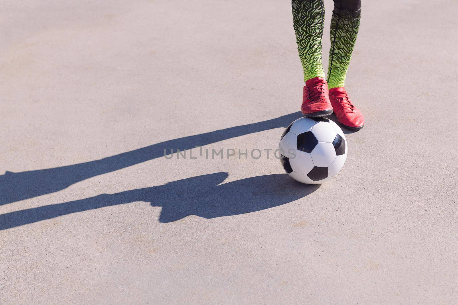 detail of a footballer feet with one foot on the ball in a concrete soccer field, concept of healthy lifestyle and urban sport in the city, copy space for text