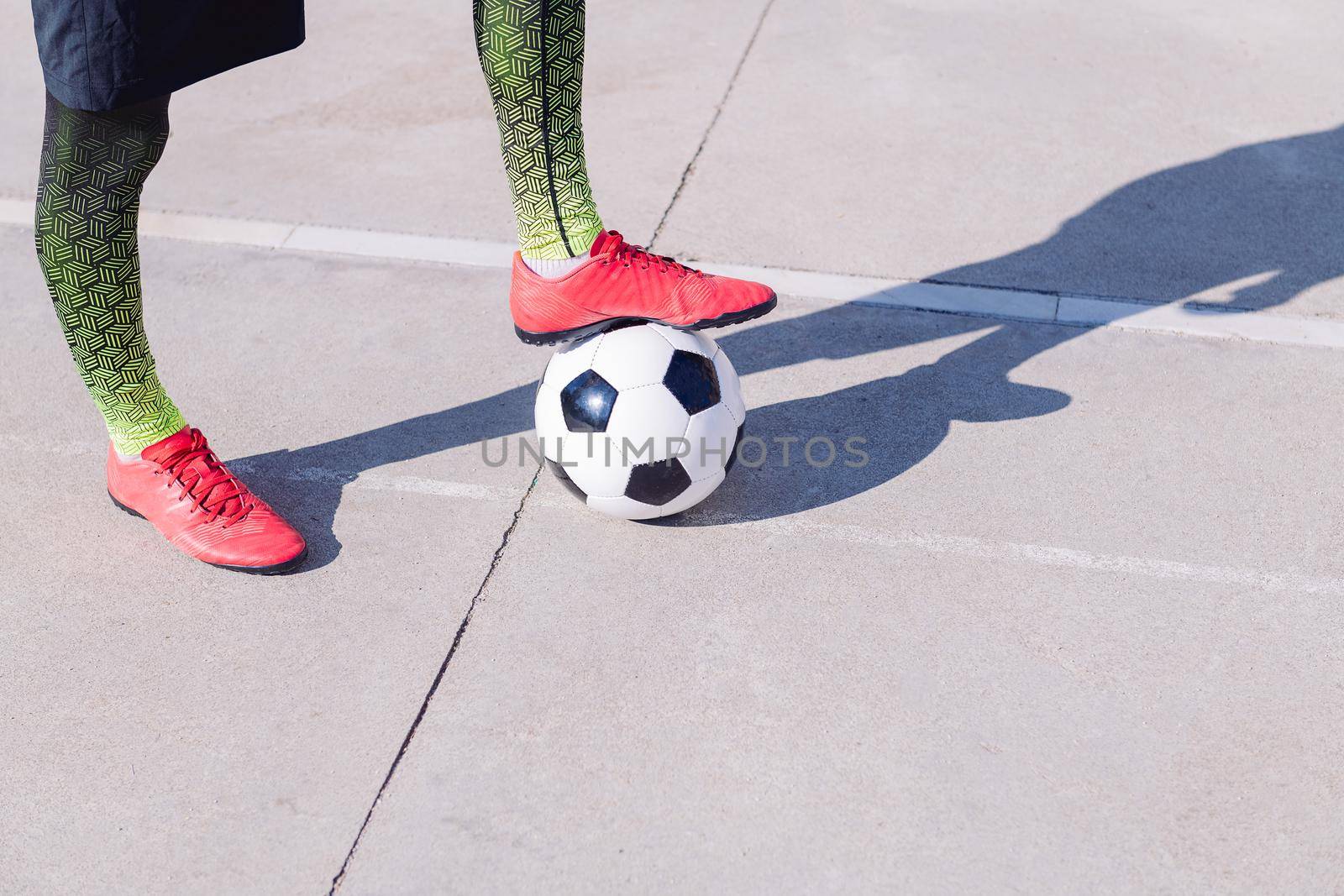 detail of a soccer player feet with one foot on the ball in a concrete football field, concept of healthy lifestyle and urban sport in the city, copy space for text