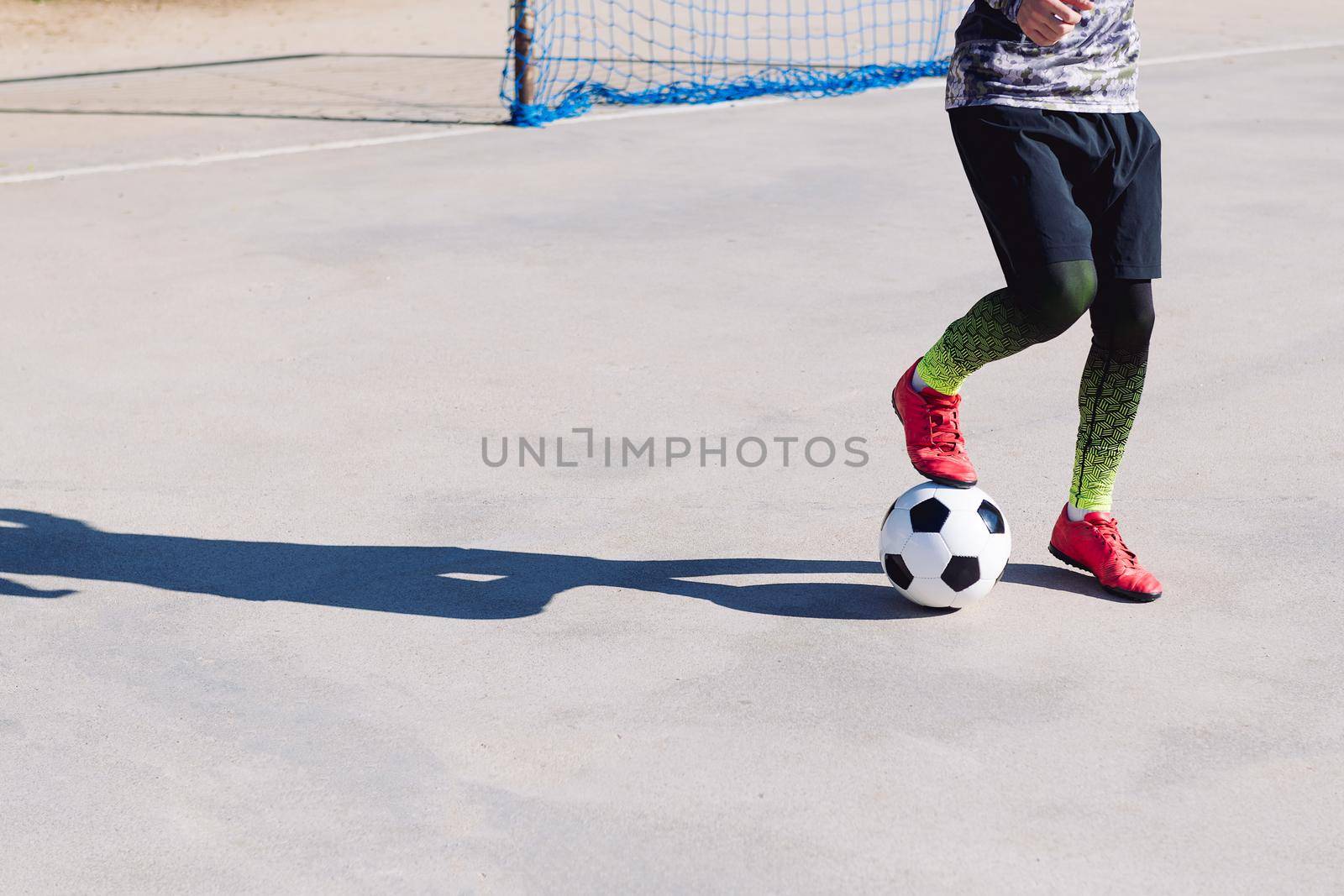 unrecognizable football player stepping on the ball in a concrete football court, concept of healthy lifestyle and urban sport in the city, copy space for text
