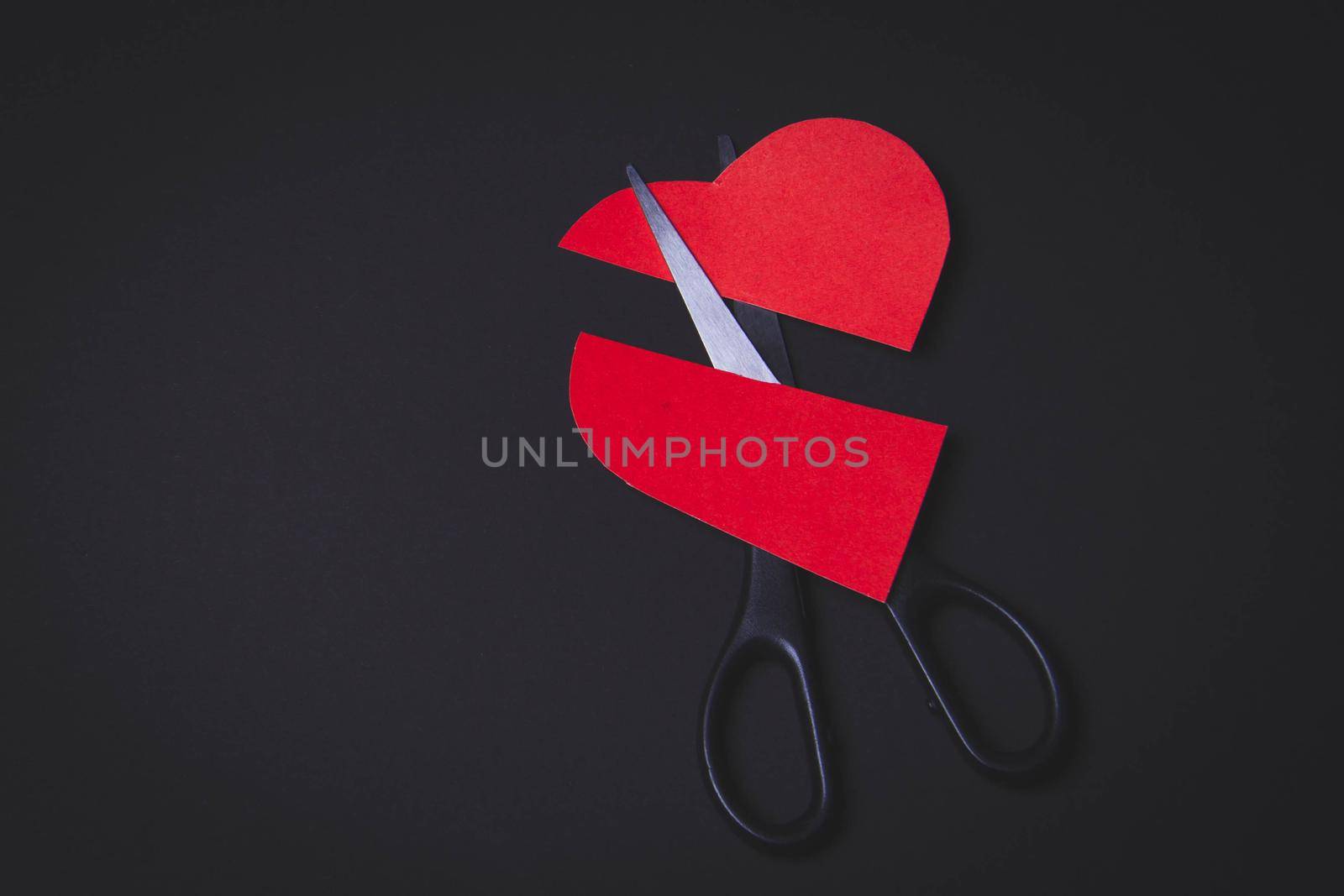 Broken heart. Divorce of a married couple. Broken marriage. Heart in hand and scissors.