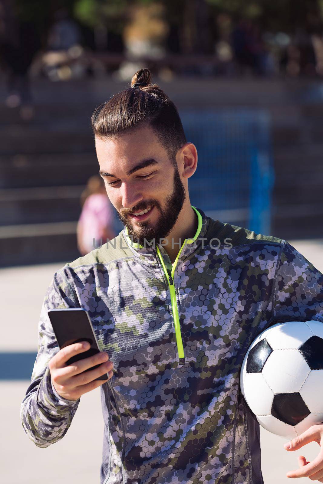 sportsman with a soccer ball consulting his phone by raulmelldo