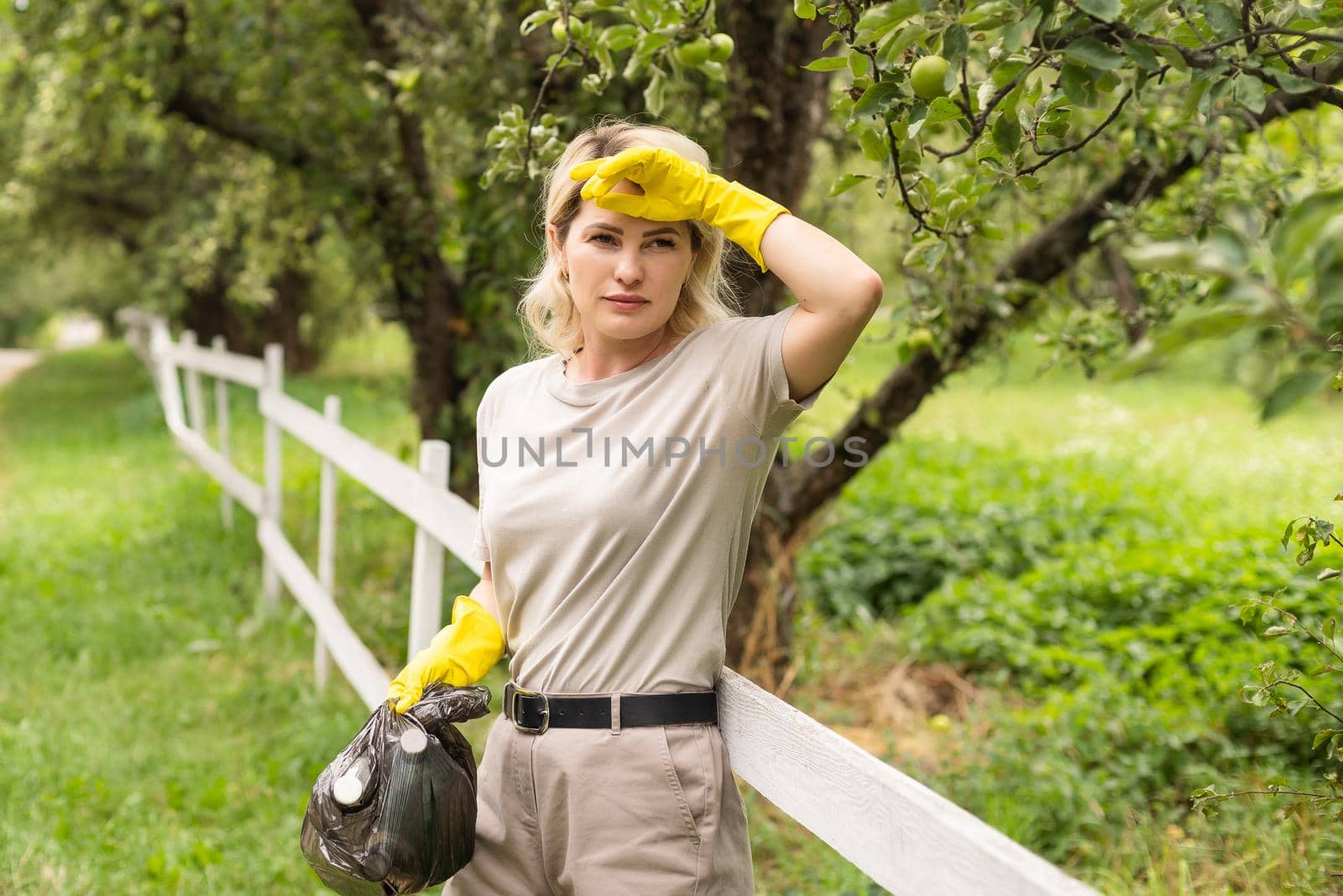 woman picking up garbage and putting it in plastic black bag