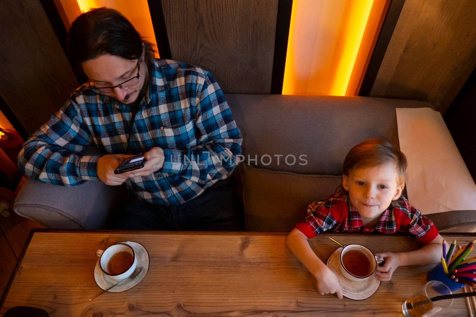 Little boy with your father drinking from a cup tea in a cafe. High quality photo