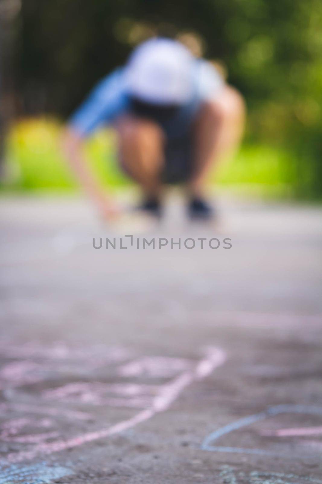 Children draw with chalk on the road. Children's creativity on the street. Entertainment in nature.