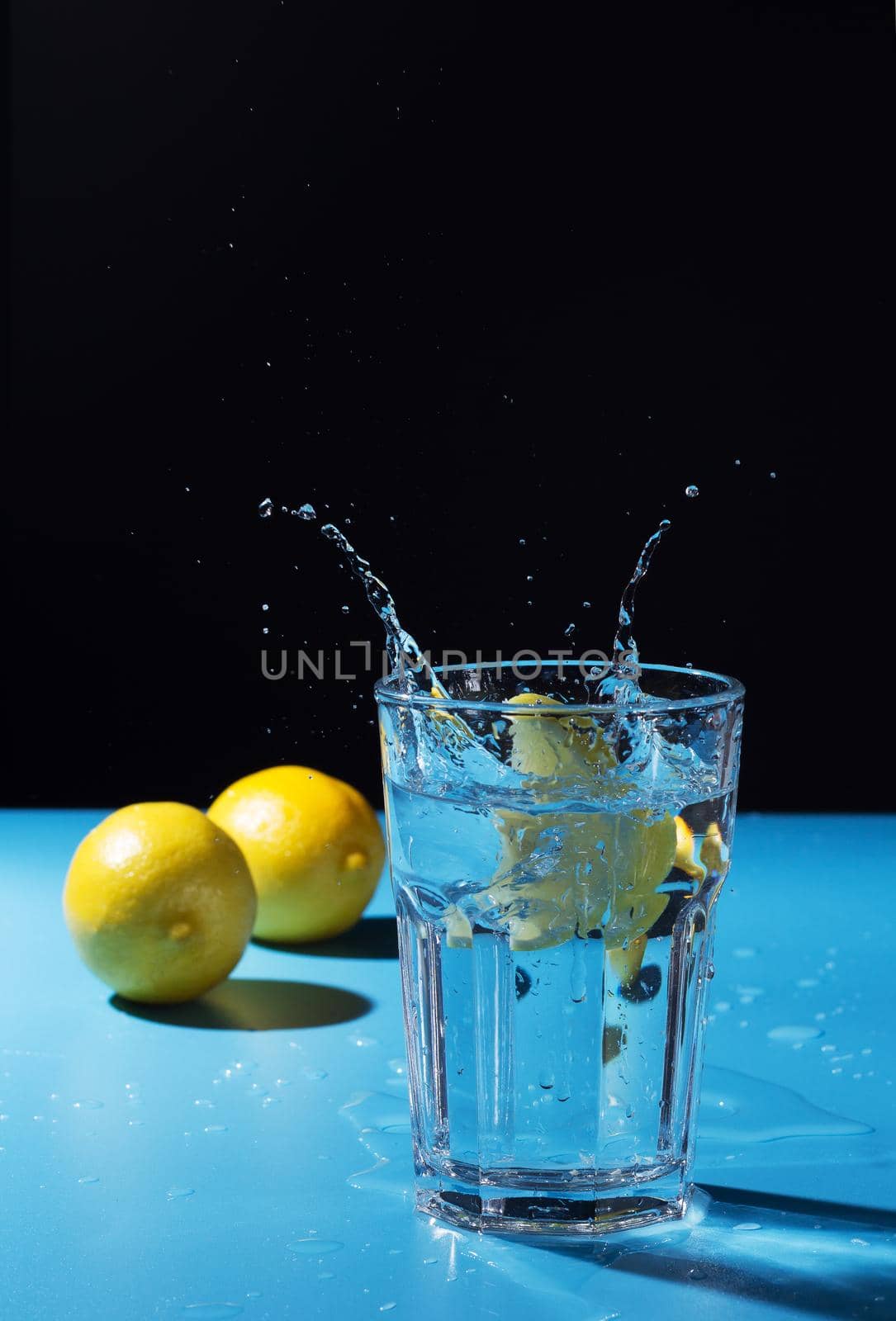 Water splash with lemon on blue and black background by lara29