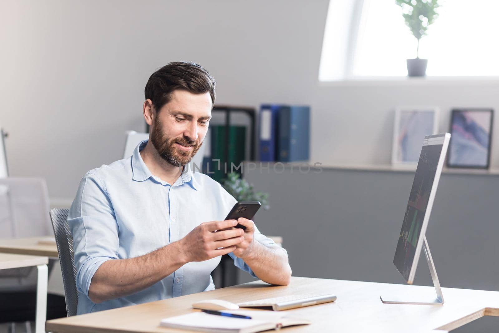 Young man with a beard, freelancer, manager, worker talking on a cell phone in the office by voronaman