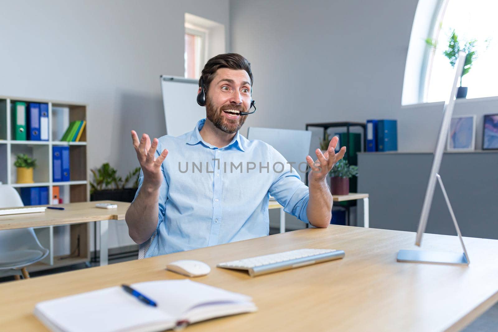 Portrait of a happy businessman, man working remotely, using a headset for a video call by voronaman