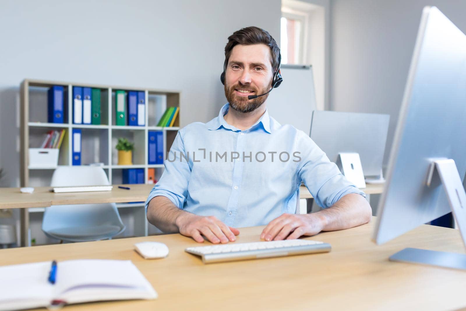 Portrait of a happy businessman, man working remotely, using a headset for a video call by voronaman