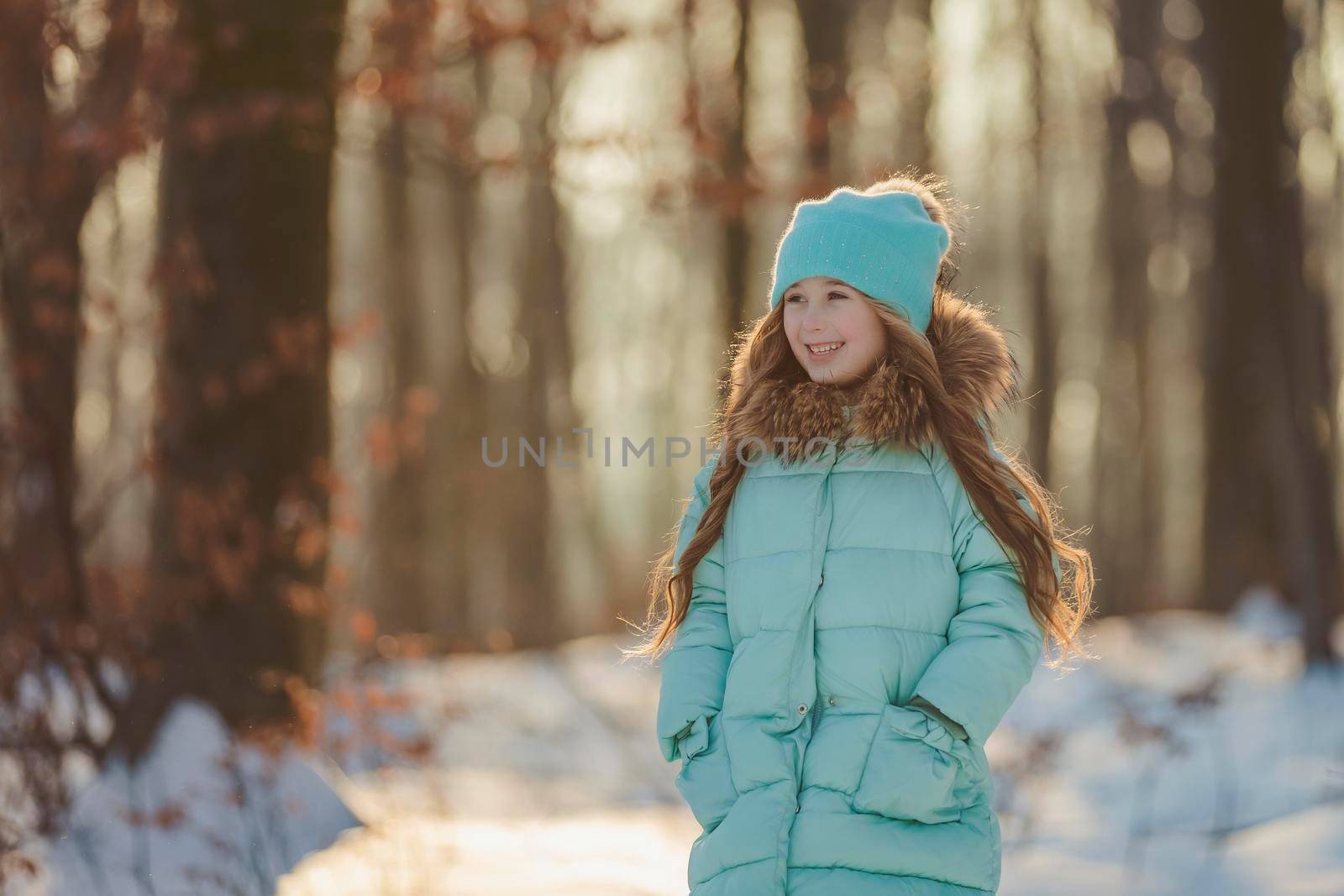 little girl in a winter forest and turquoise-colored clothes