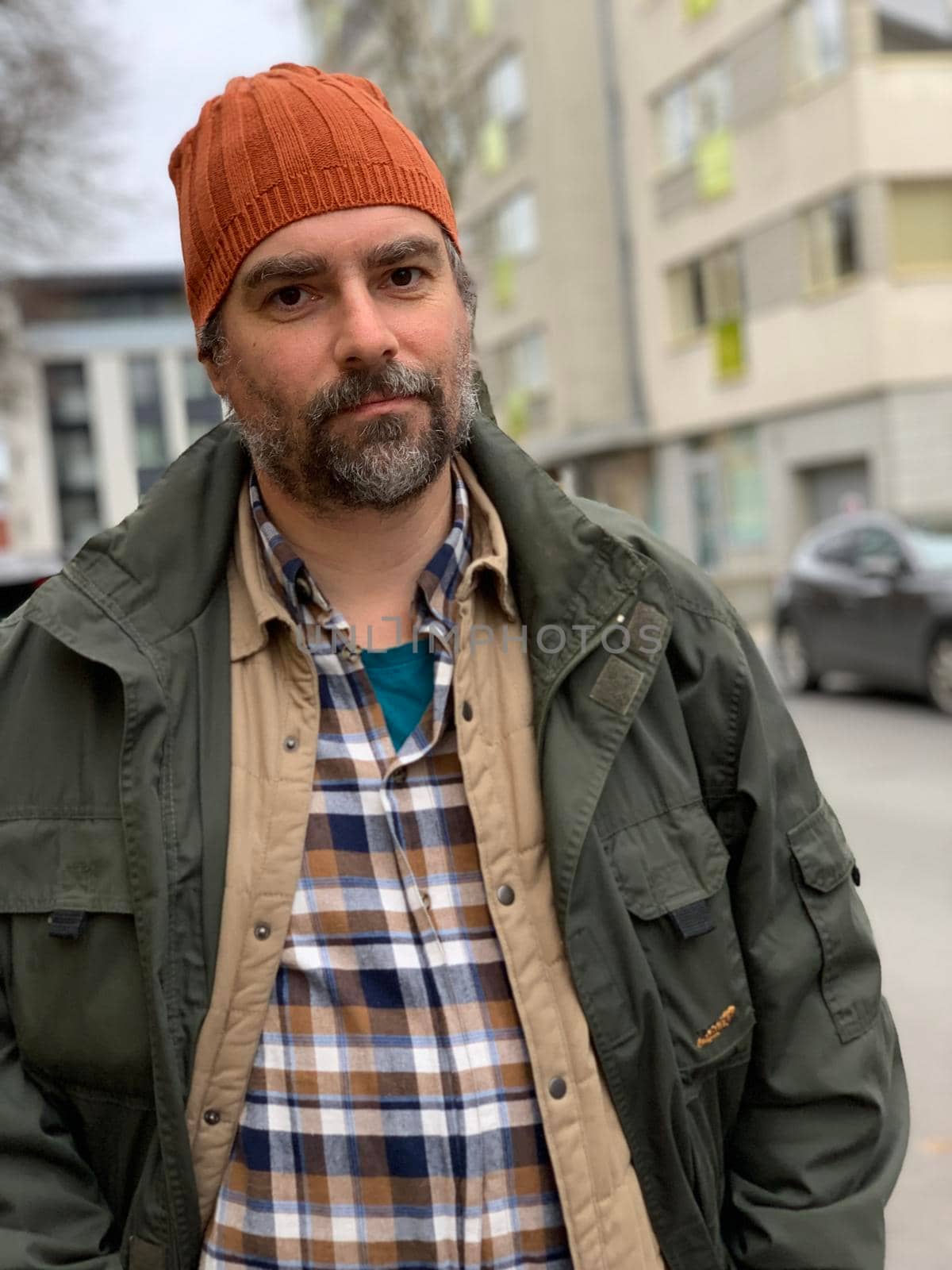 Portrait of a mature man wearing orange beanie hat standing outside by Varaksina