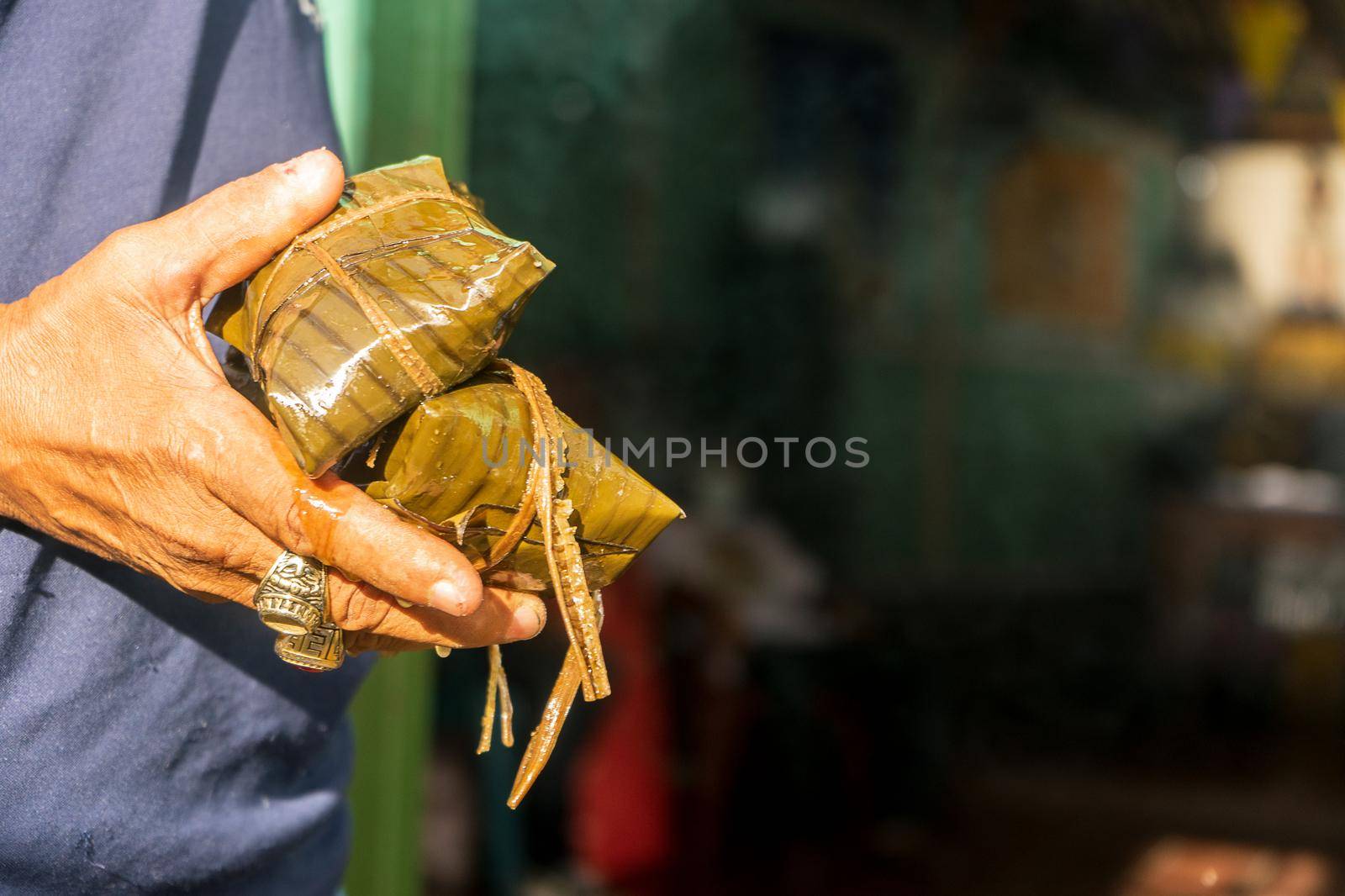 Hand of a Nicaraguan man holding two nacatamales by cfalvarez
