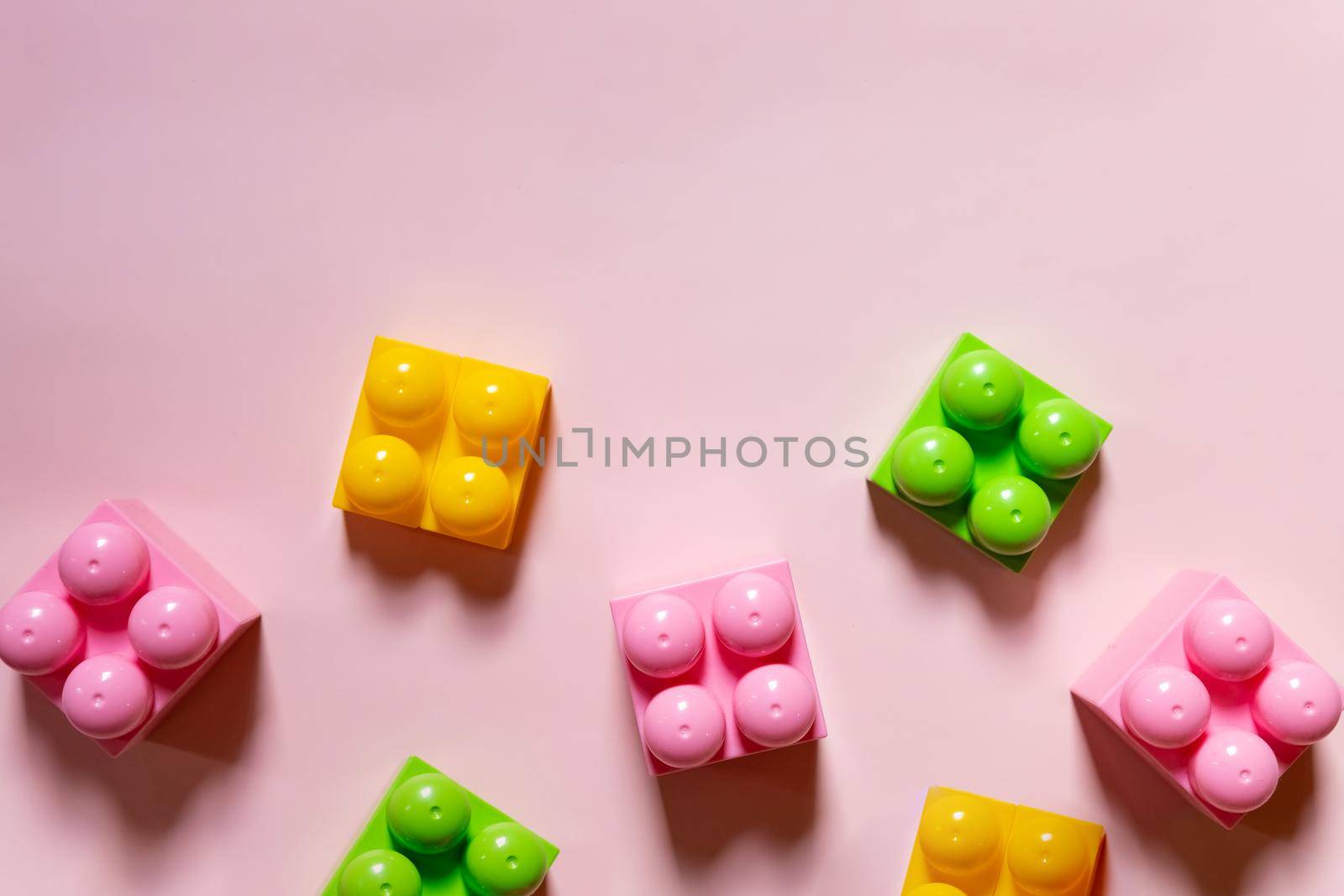 Colorful plastic building blocks flat lay. Yellow background. Child developing game. Pattern
