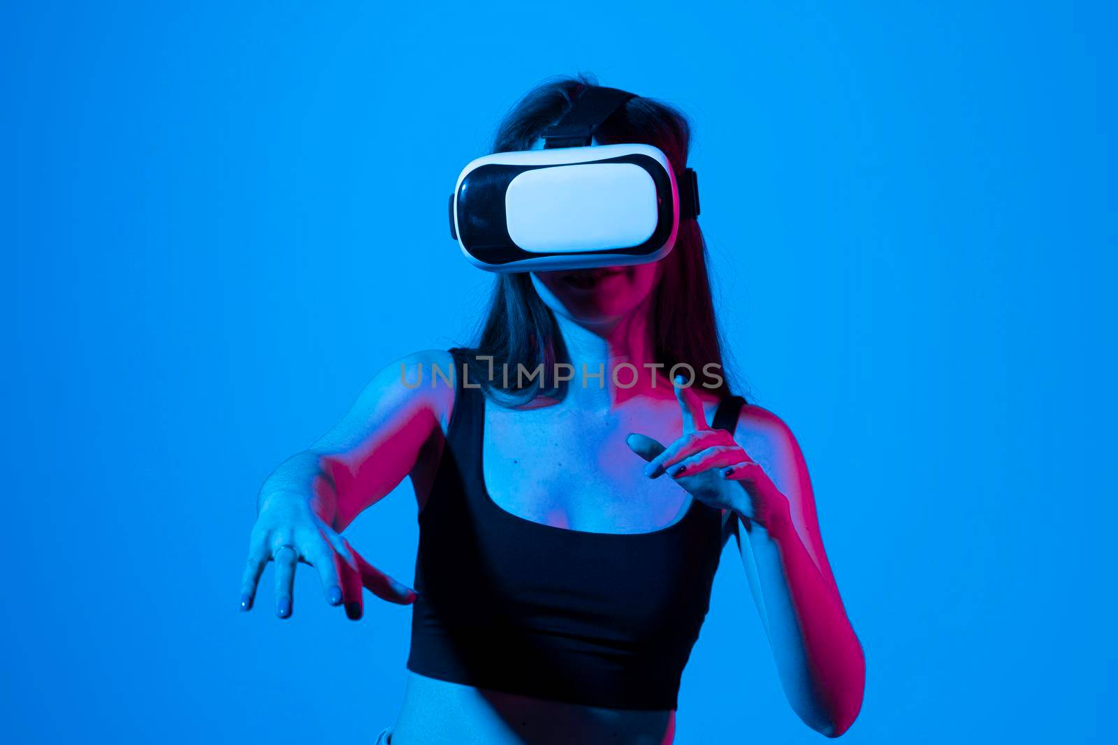 Young brunette woman wearing VR headset looking at art objects while visiting modern exhibition using augmented reality technology. Future technology concept
