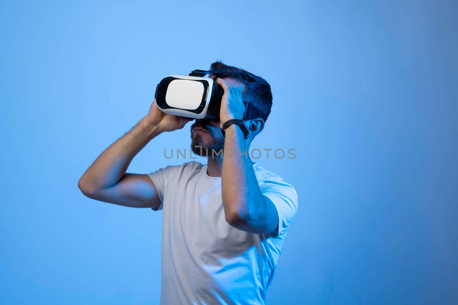 Bearded young man using VR glasses, touching with a hand copy space free space, playing virtual video games with friends online