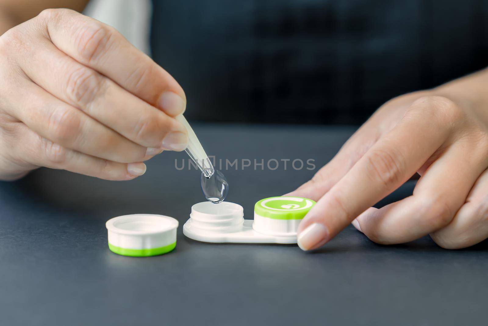 Woman takes contact lens out of container with tweezers, close-up, side view by Laguna781