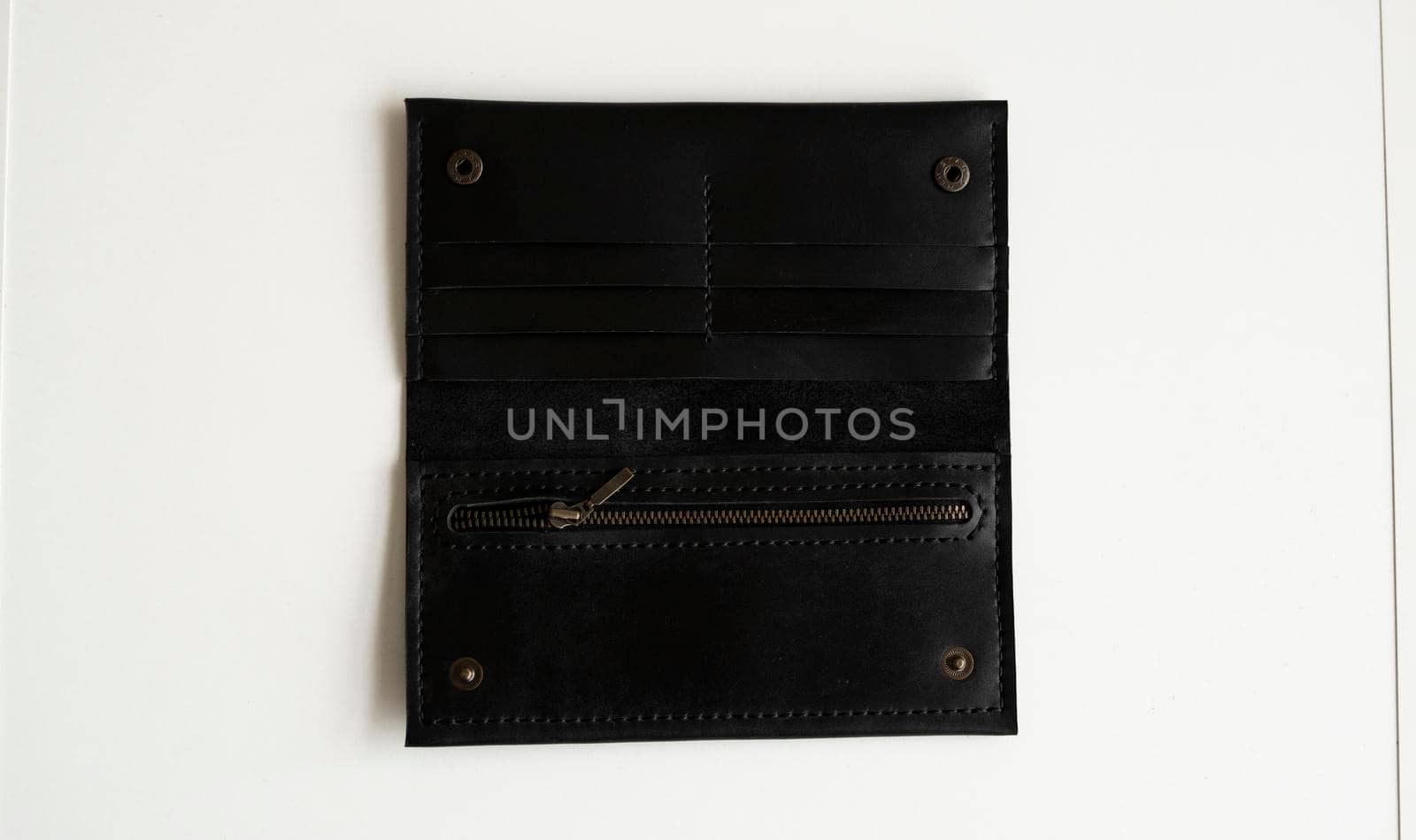 Man's handmade wallet on a white surface. Wallet made of genuine black leather with a slots for cards and big zip pocket on a white background. Accessories for men. by vovsht