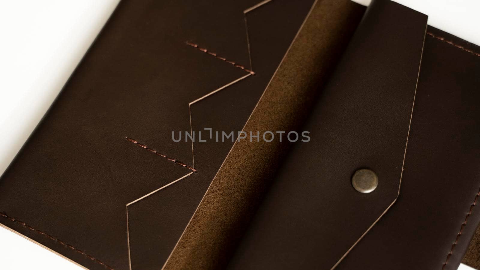 Man's handmade wallet on a white surface. Wallet made of genuine brown leather on a white background. Accessories for men