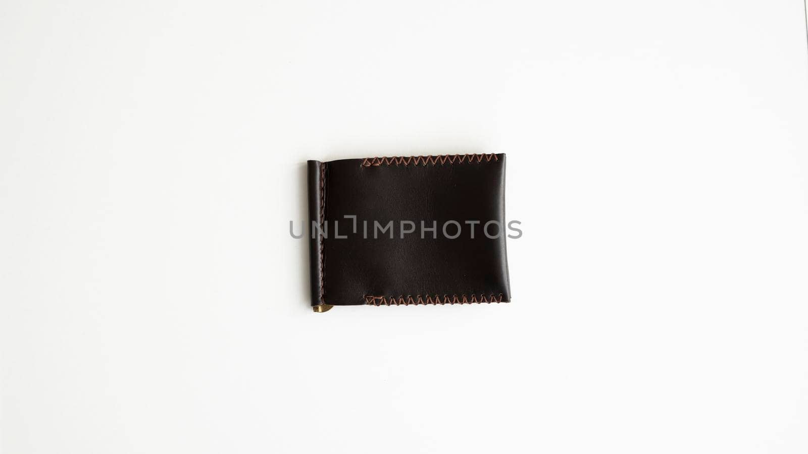 Brown men's money clip handmade leather wallet. Empty money clip wallet with a two pockets for cards lies on a white table. Selective focus, copy space. by vovsht