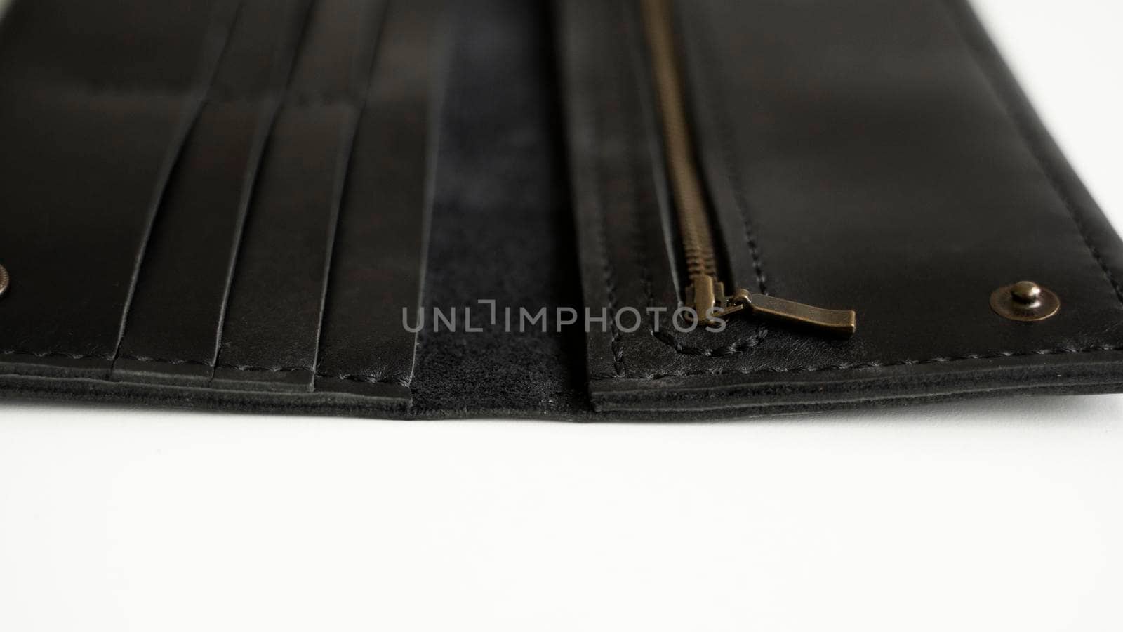 Details of man's handmade wallet on a white surface. Wallet made of genuine black leather with a slots for cards and big zip pocket on a white background. Accessories for men