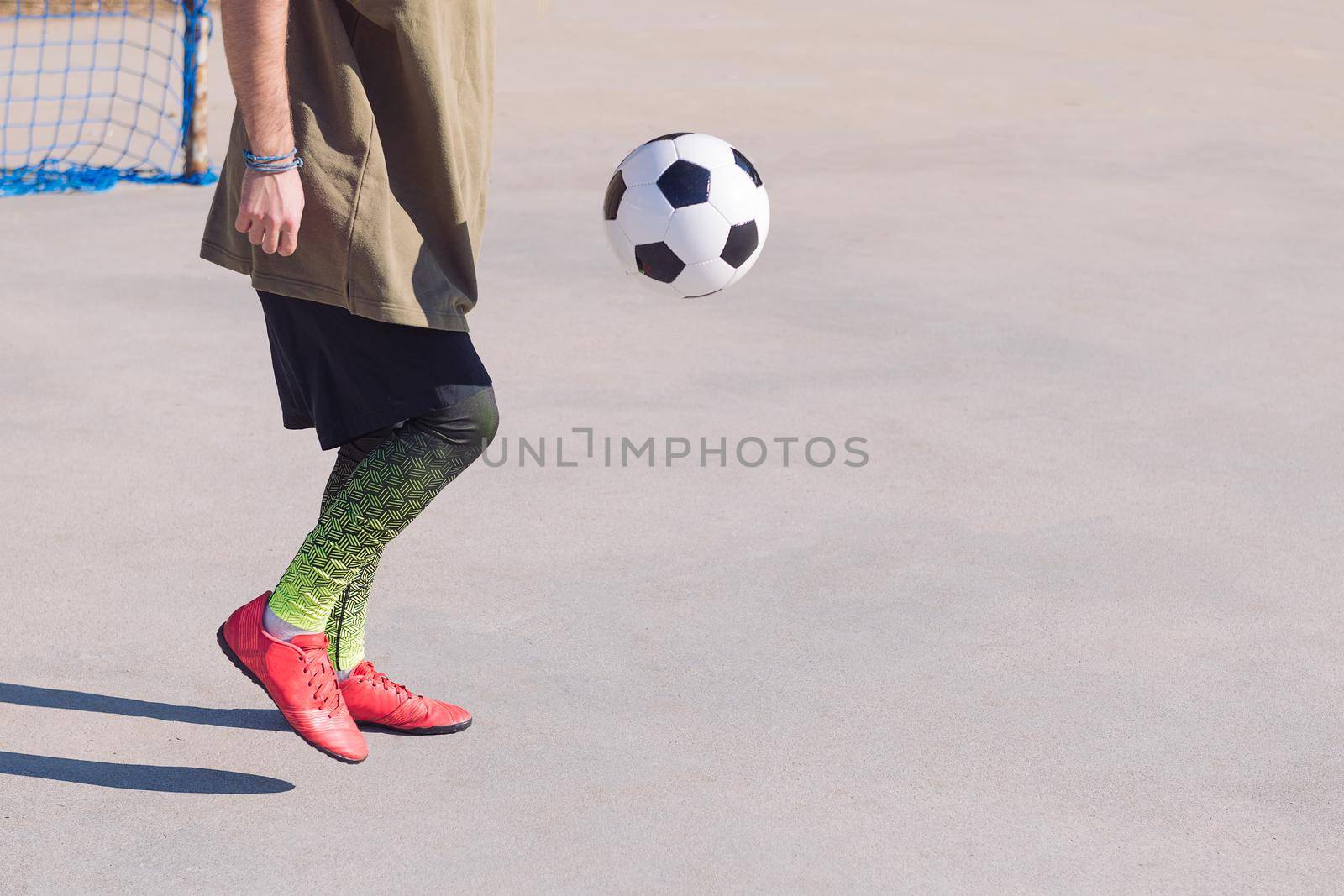 unrecognizable football player playing the ball in a concrete soccer field, concept of healthy lifestyle and urban sport in the city, copy space for text
