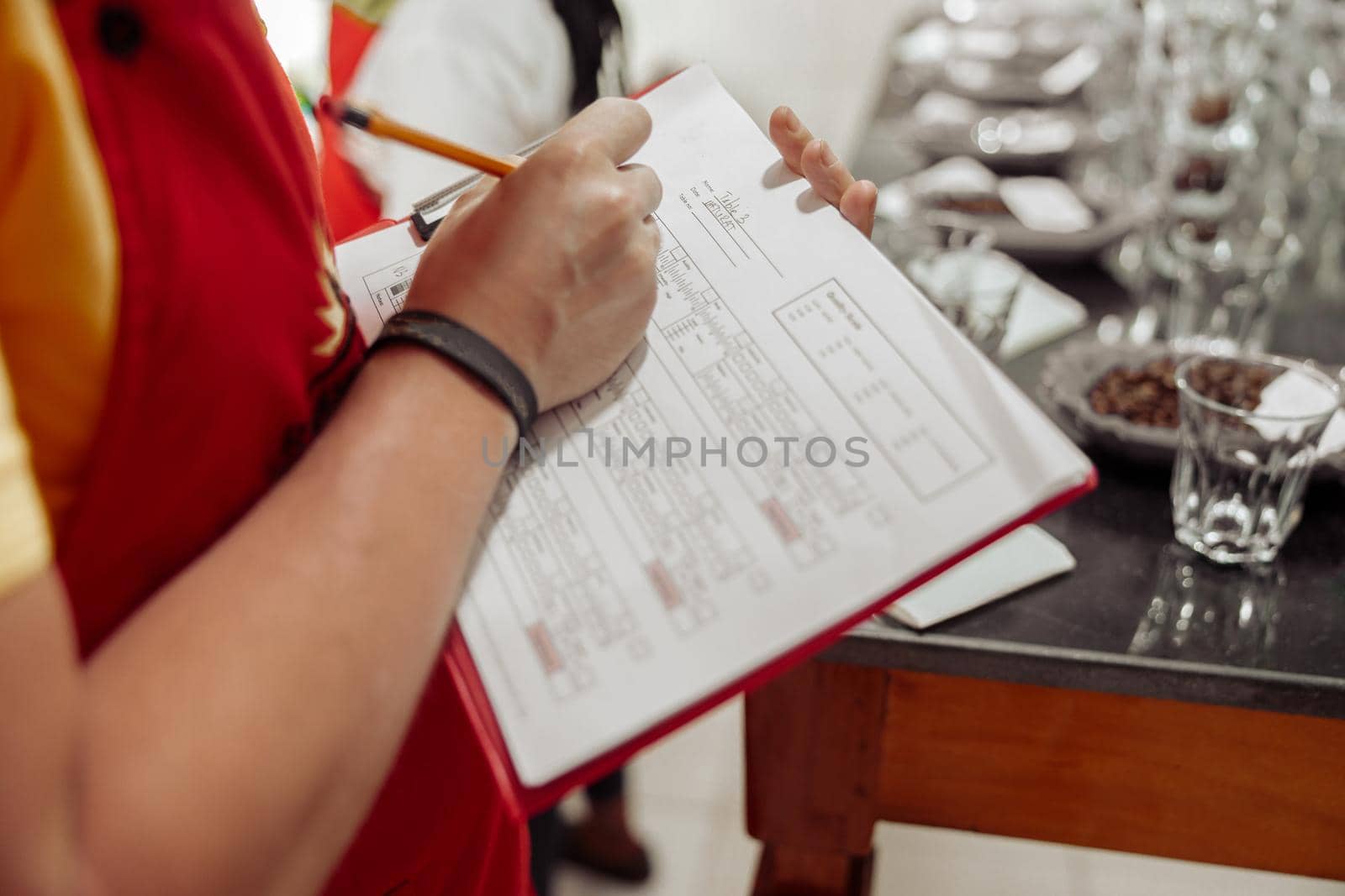 Close up of man making notes point by point while tasting coffee