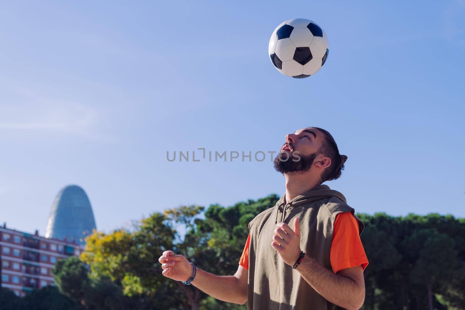 portrait of a football player playing giving head hits to the the ball in the city, concept of healthy lifestyle and urban sport in the city, copy space for text