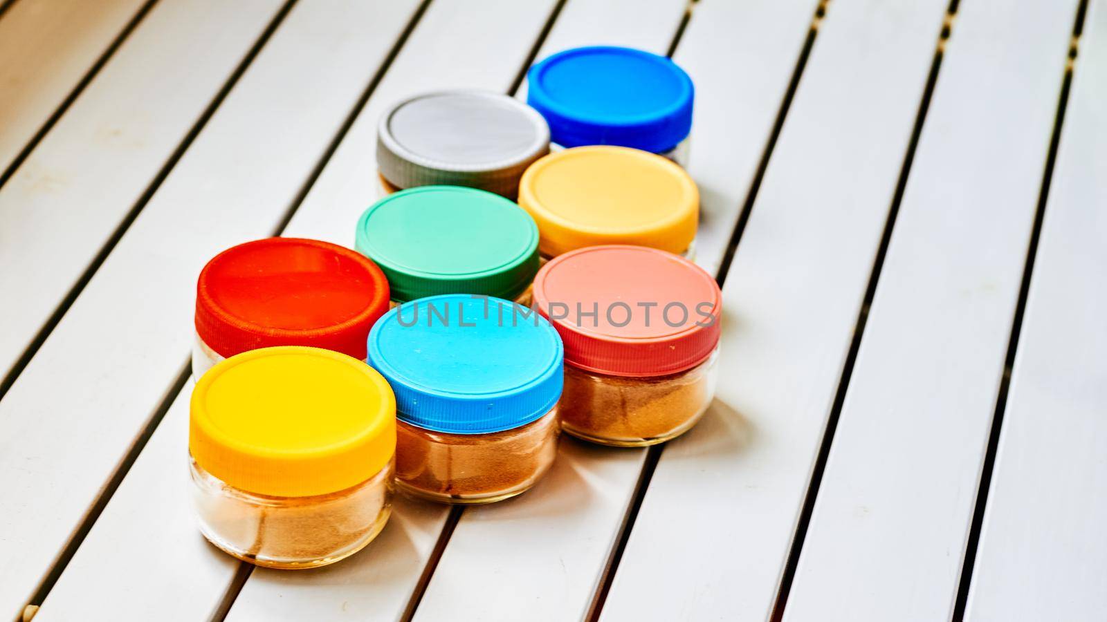 Several glass containers for different cooking spices on a white striped table by jovani68