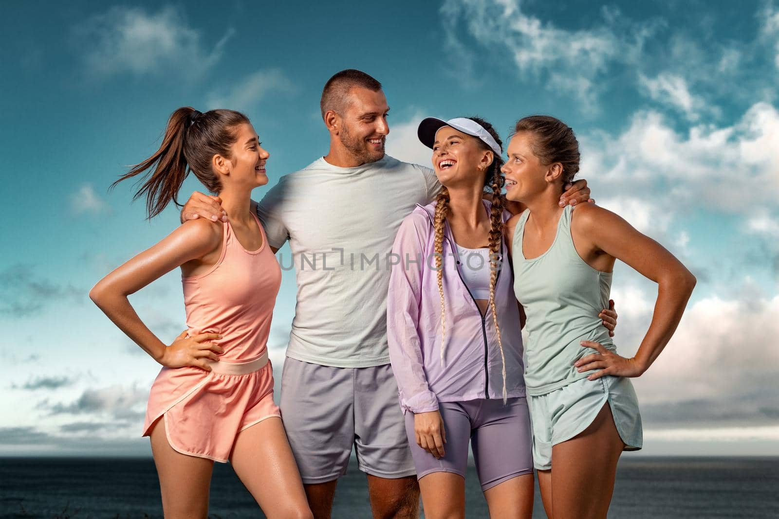 Smiling woman and man fitness team. A happy group of runners rest after running along the sea coast early in the morning