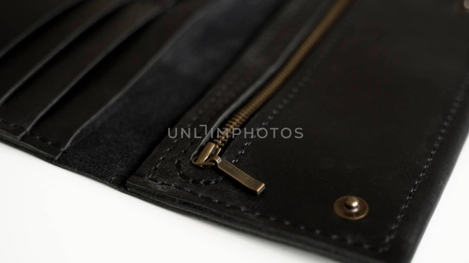 Details of man's handmade wallet on a white surface. Wallet made of genuine black leather with a slots for cards and big zip pocket on a white background. Accessories for men. by vovsht