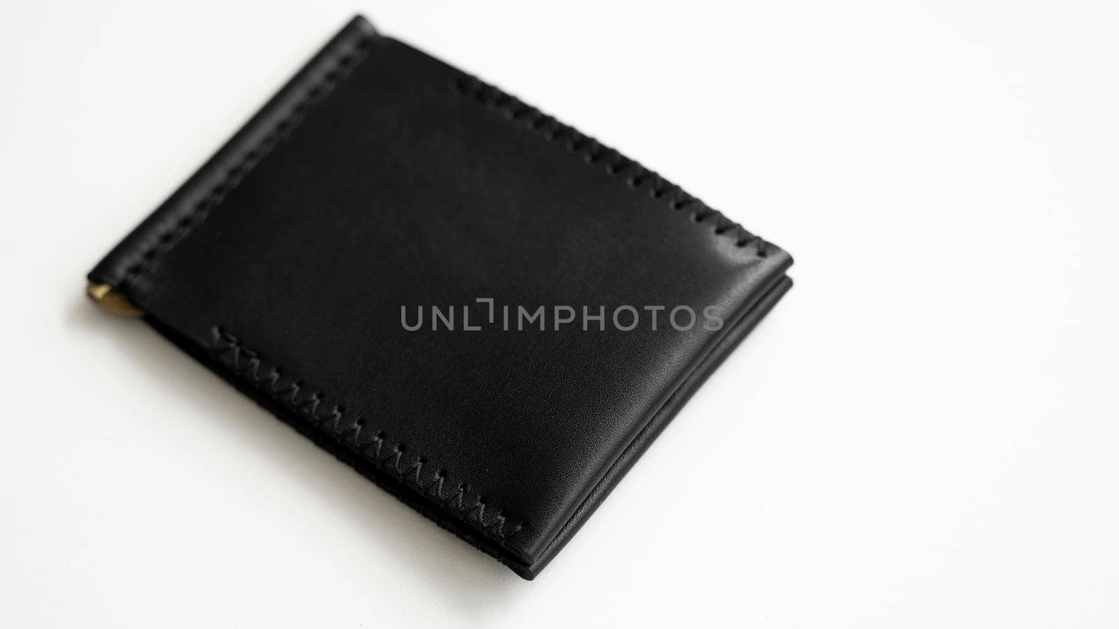 Brown men's money clip handmade leather wallet. Empty money clip wallet with a two pockets for cards lies on a white table. Selective focus, copy space. by vovsht