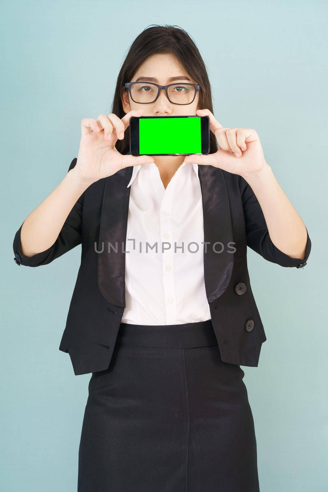 Young women in suit holding her  smartphone mock up green screen standing against blue background