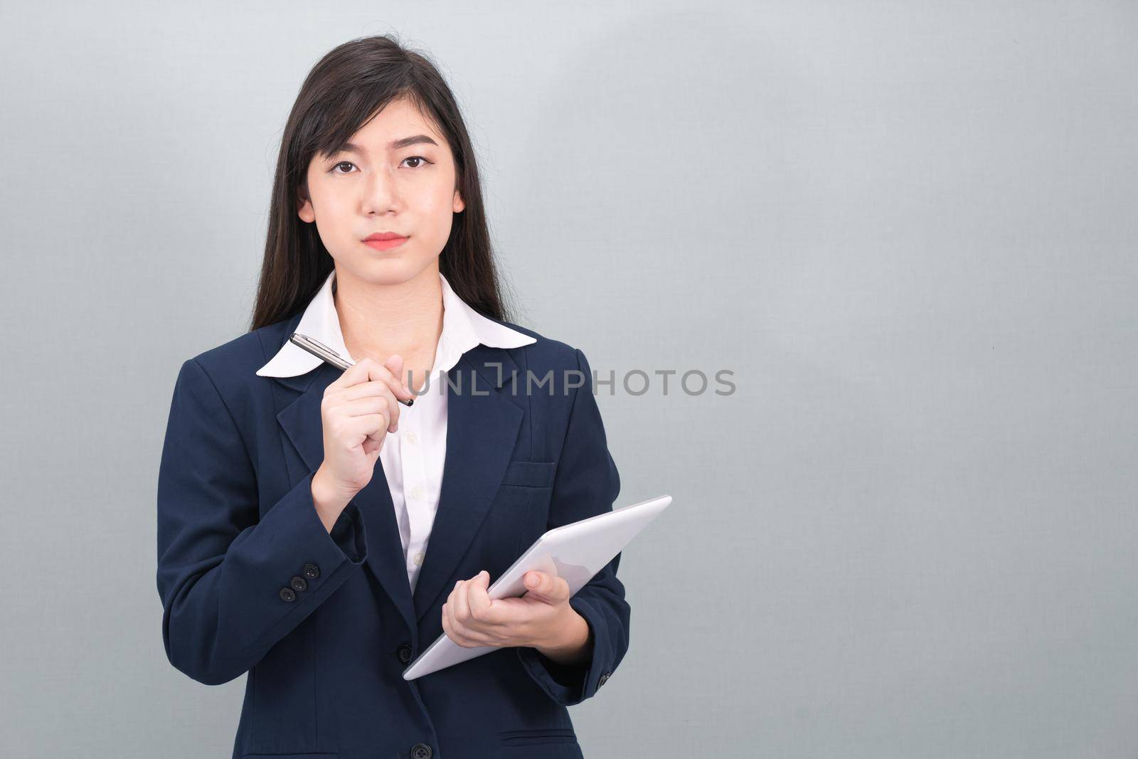 Woman in suit using computer digital tablet isolated on gray background