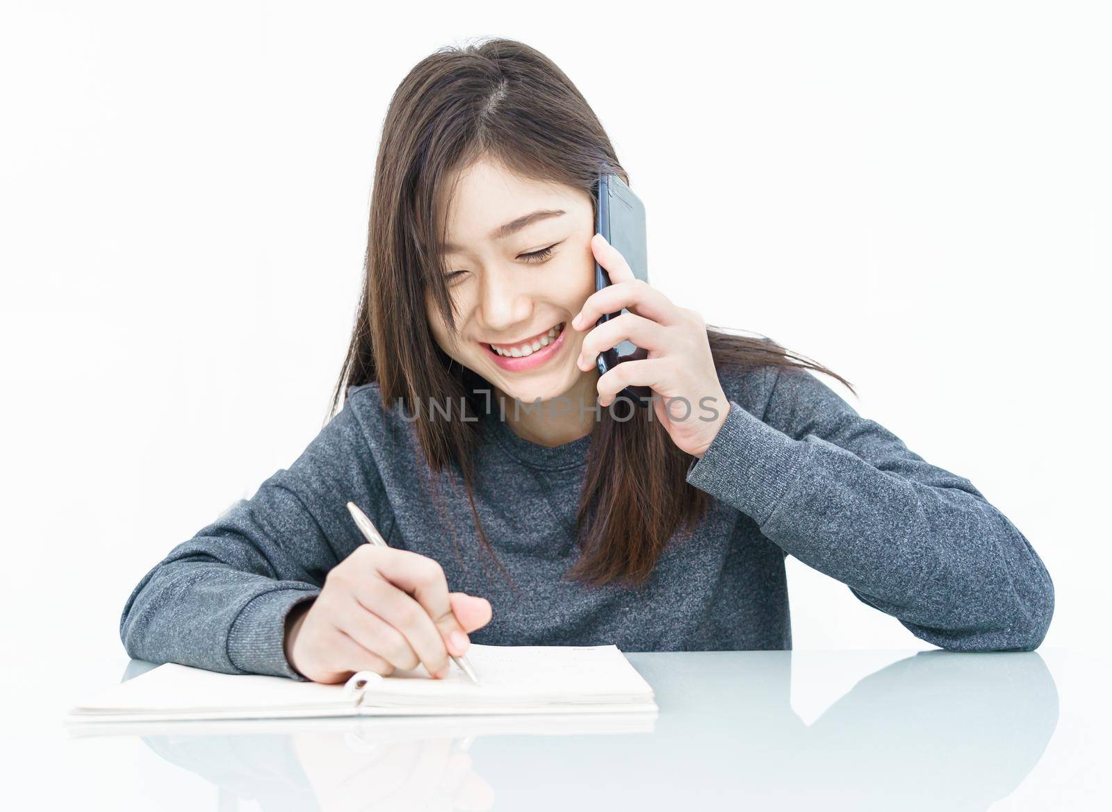 Woman using mobile phone and  writing notebook  by stoonn