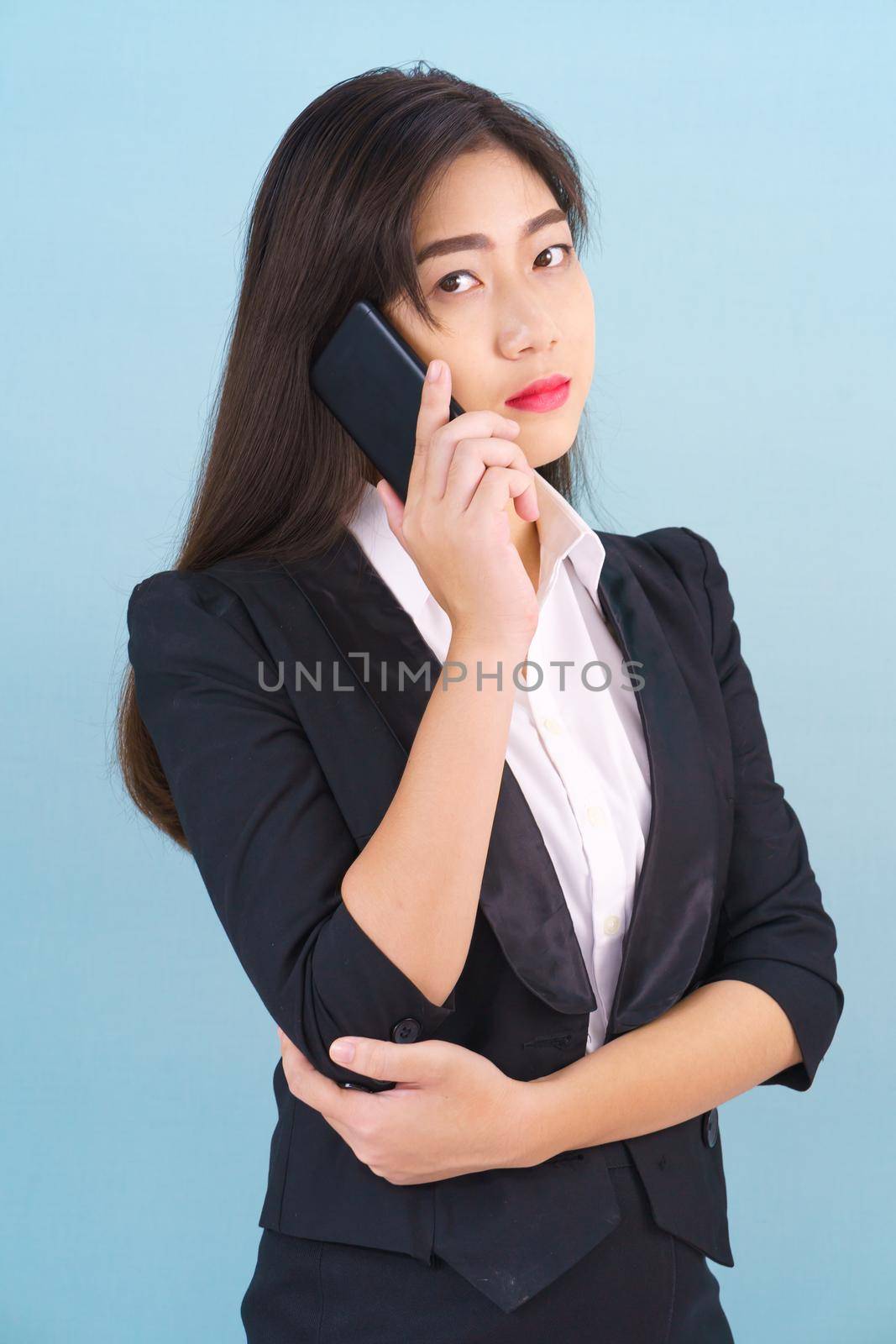 Women in suit holding smartphone against blue background by stoonn