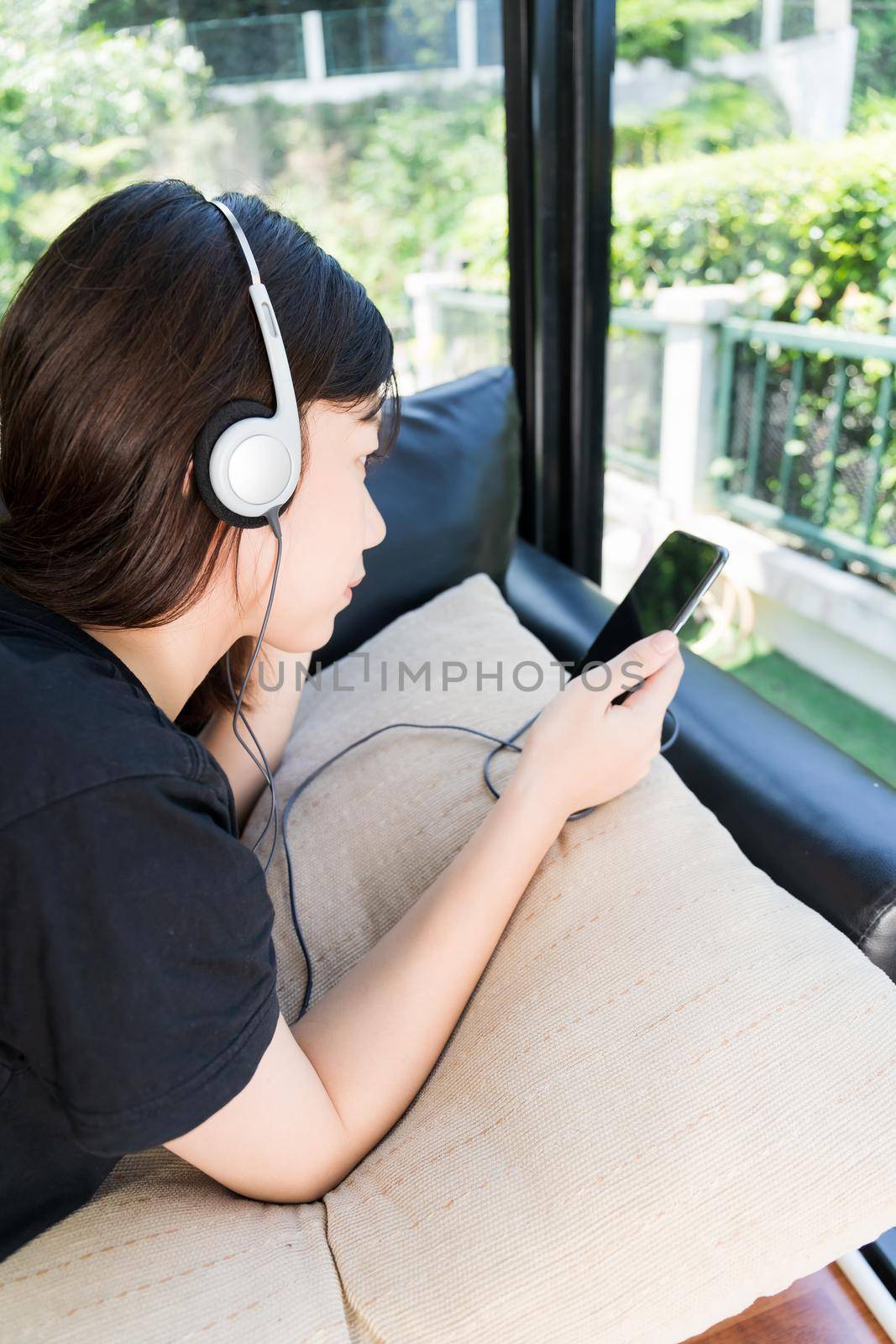 Young girl listening to music from mobile phone in living room by stoonn