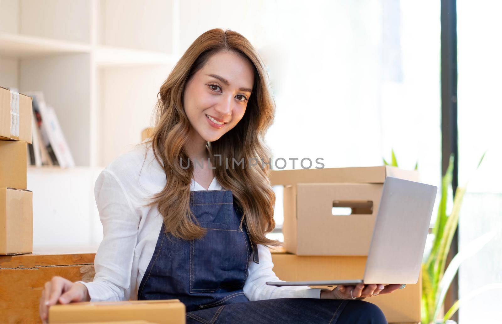 Portrait of Asian young woman SME working with a box at home the workplace.start-up small business owner, small business entrepreneur SME or freelance business online and delivery concept. by wichayada