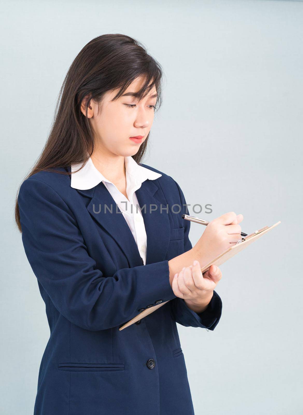 Portrait of Asian woman long hair and wearing suit  with clipboard and pen in hands thinking about success, isolated on white background