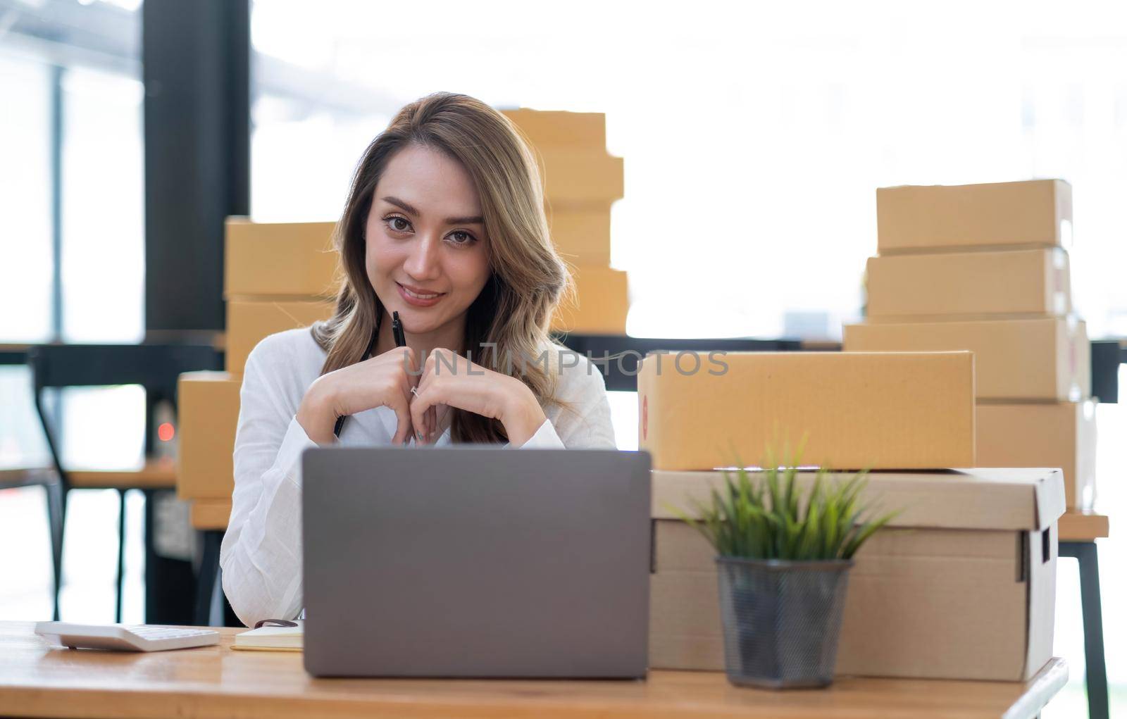 Portrait of Asian young woman SME working with a box at home the workplace.start-up small business owner, small business entrepreneur SME or freelance business online and delivery concept. by wichayada