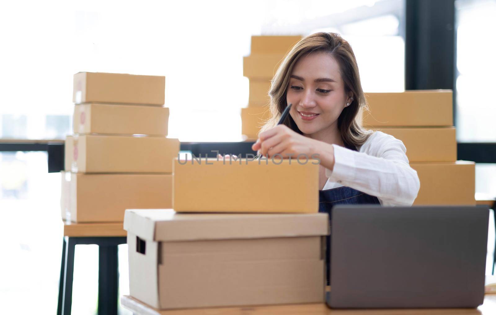 Portrait of Asian young woman SME working with a box at home the workplace.start-up small business owner, small business entrepreneur SME or freelance business online and delivery concept. by wichayada