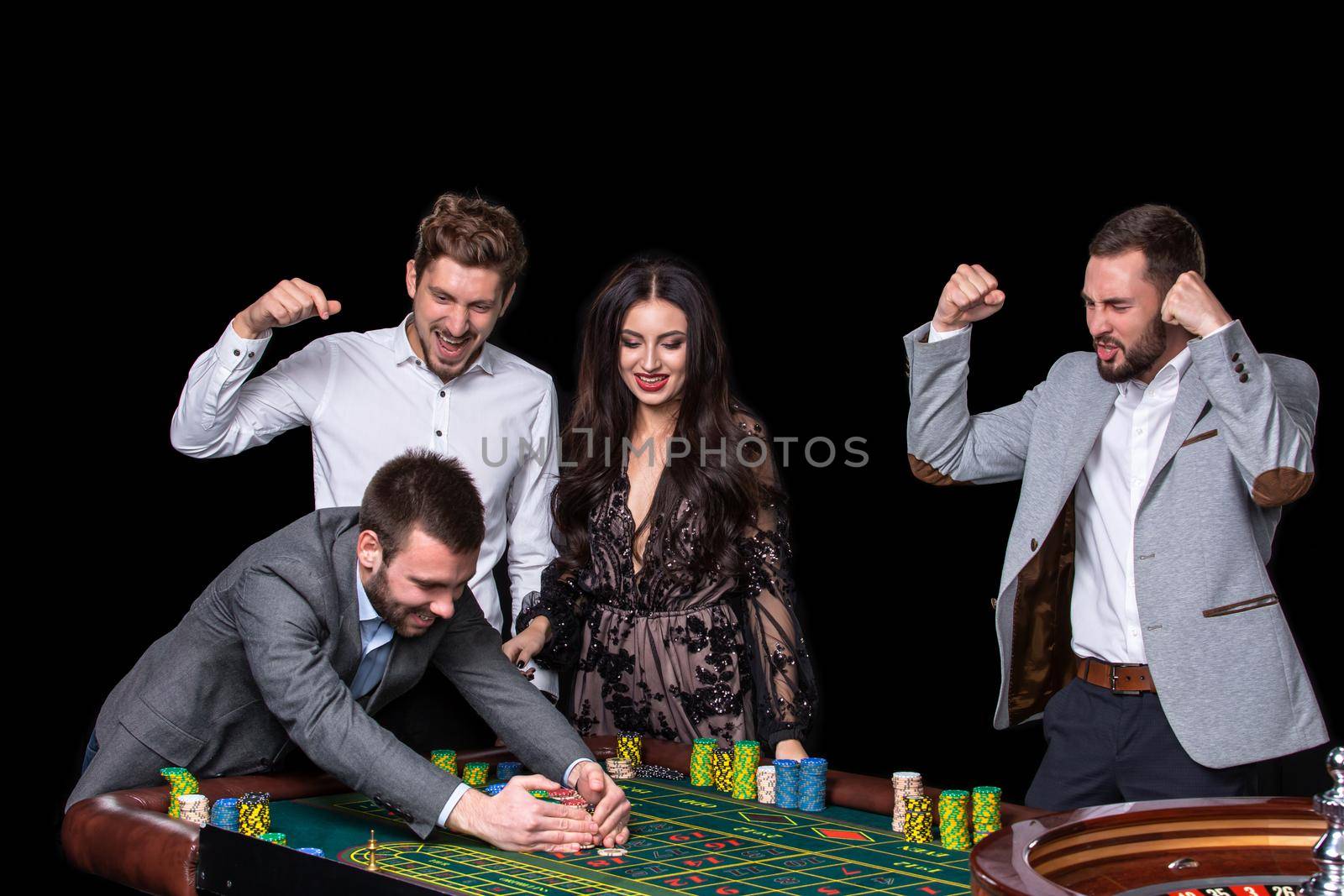 Upper class friends gambling in a casino. Roulette. Black background