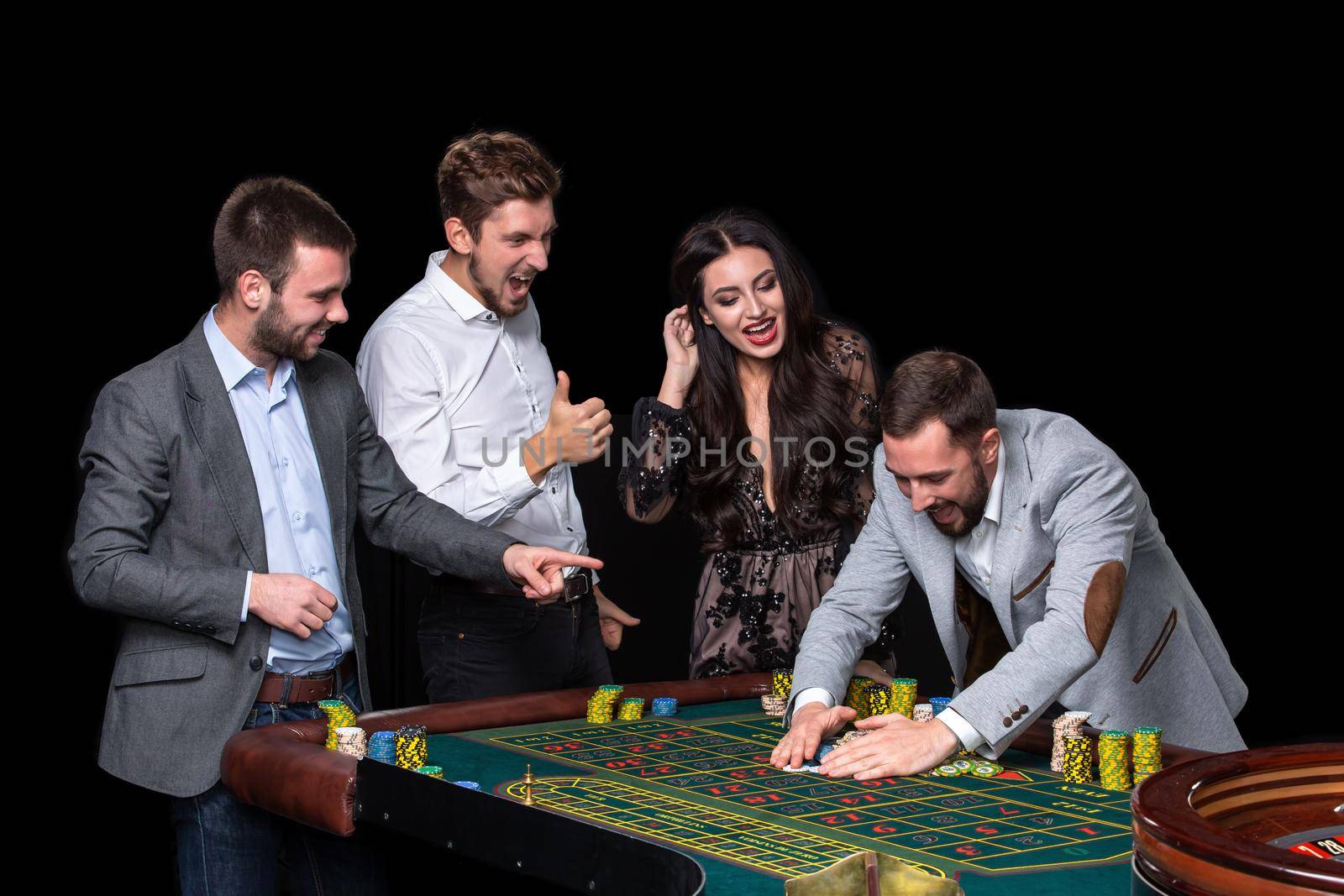 Upper class friends gambling in a casino. Roulette. Black background