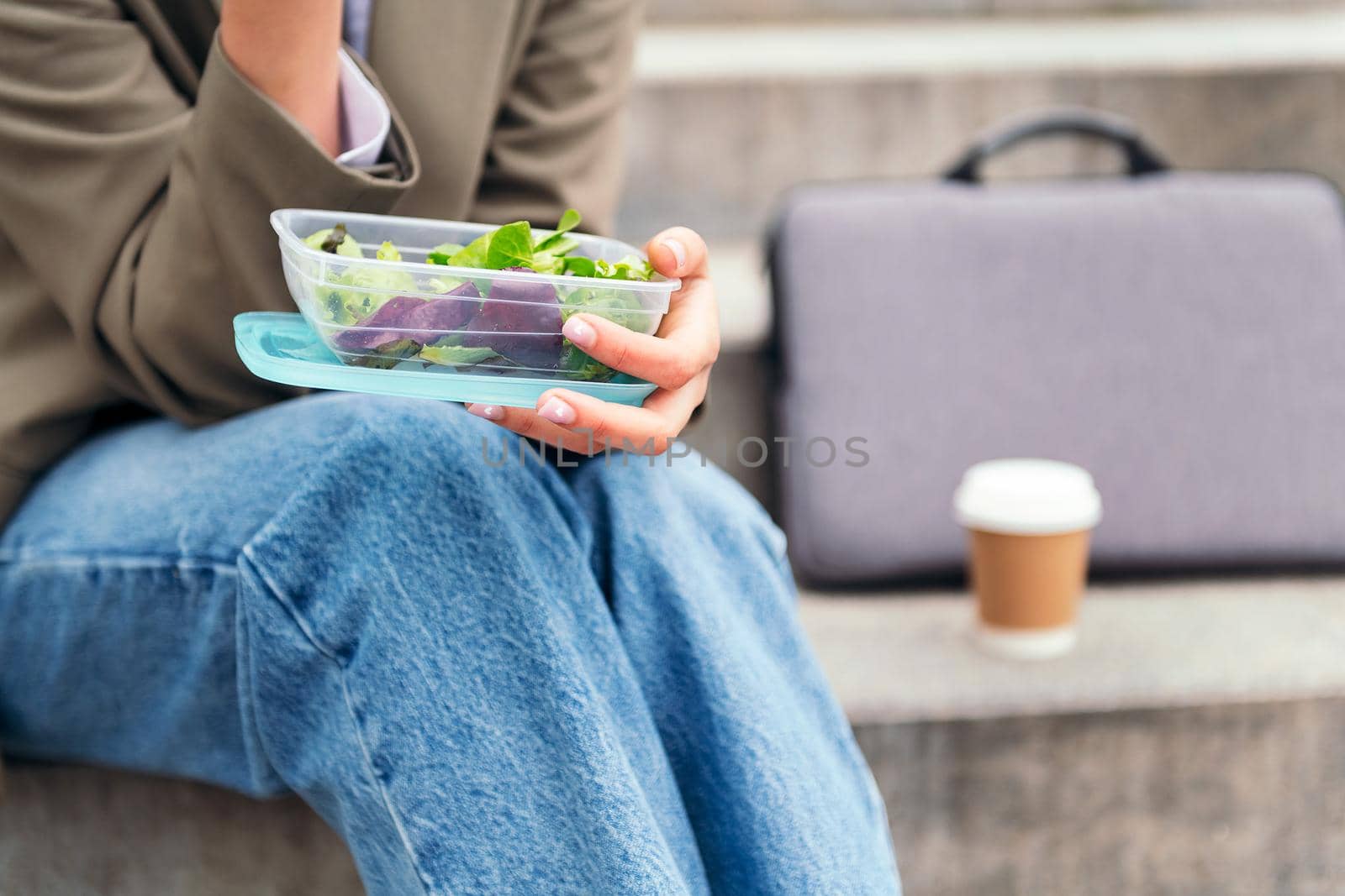 close up of a woman's hand holding a lunch box with salad, concept of urban lifestyle and healthy food, copy space for text