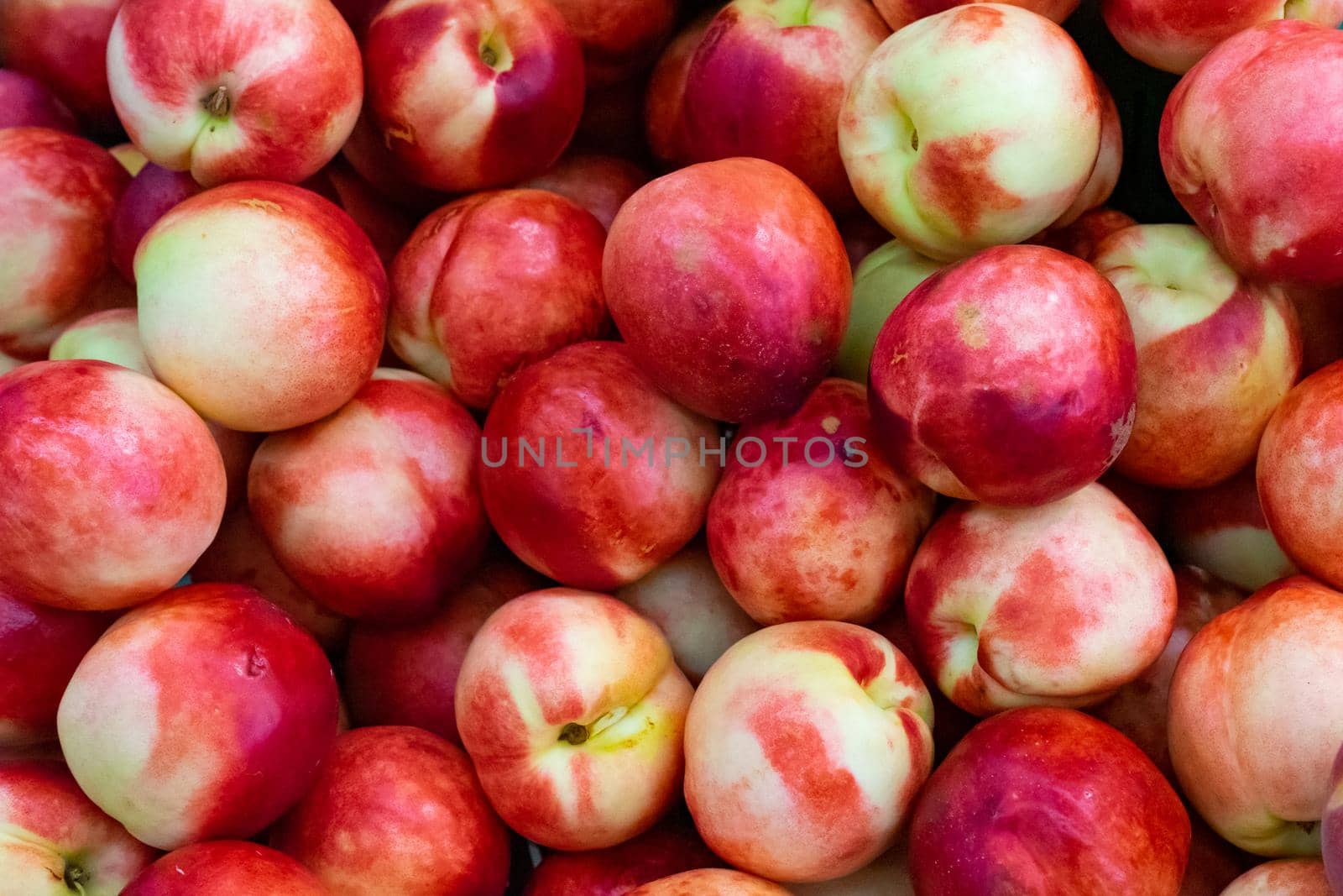 Lots of bright ripe peaches. Red nectarine close-up.