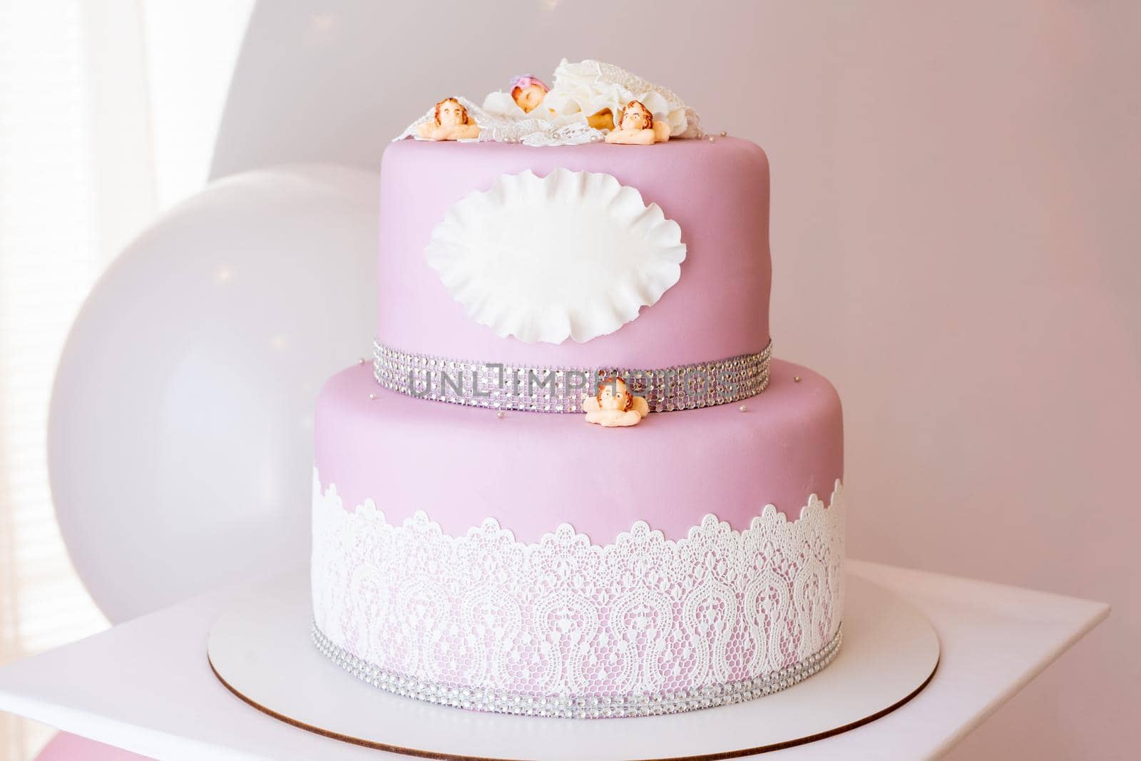 Two-tiered pink cake with a place for an inscription and little angels. Copy space by Serhii_Voroshchuk